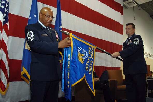 Chief Master Sgt. Kenneth Funderburg, 55th Wing command chief, attaches his commemorative ribbon to the Offutt Chief’s Group guidon as a symbol of honor at his retirement ceremony Sept. 5 at the Airman Leadership School here. Chief Master Sgt. Scott Reed, 55th Medical Group superintendent, holds the guidon.  Chief Funderburg’s career spanned more than 30 years and involved working supply, intelligence and special operations as well as being the principal advisor to the 55th Wing commander. (U.S. Air Force Photo By Josh Plueger)