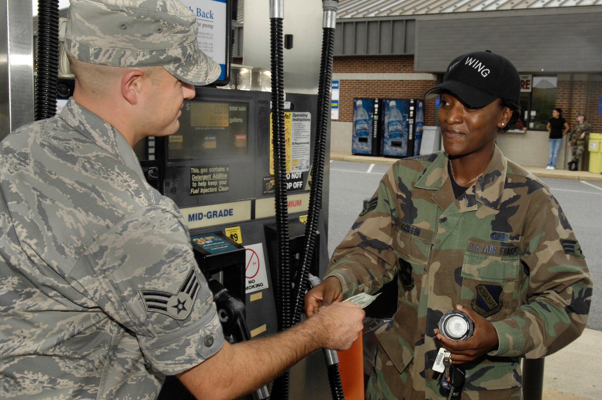 Senior Airman Dan DeCook, Airmen of Distinction events coordniator, hands $20 to Senior Airman Matoya Griffin Sept. 12 at the Bolling Shoppette. The AOD gave away a total of $240 in gas money to Air Force E-4's and below to raise awareness of the council and promote what the council does. (U.S. Air Force illistration by Senior Airmen R. Michael Longoria)