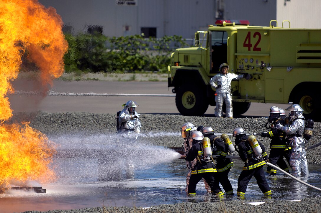 Misawa firefighter crew chiefs, Shuji Imota and Hitoshi Kashiwazaki, instruct Towada City firefighters on how to correctly extinguish a downed aircraft in case of an off base crash at Misawa Air Base, Japan, Sept. 10. The training is conducted annually. (U.S. Air Force photo/Senior Airman Chad Strohmeyer)