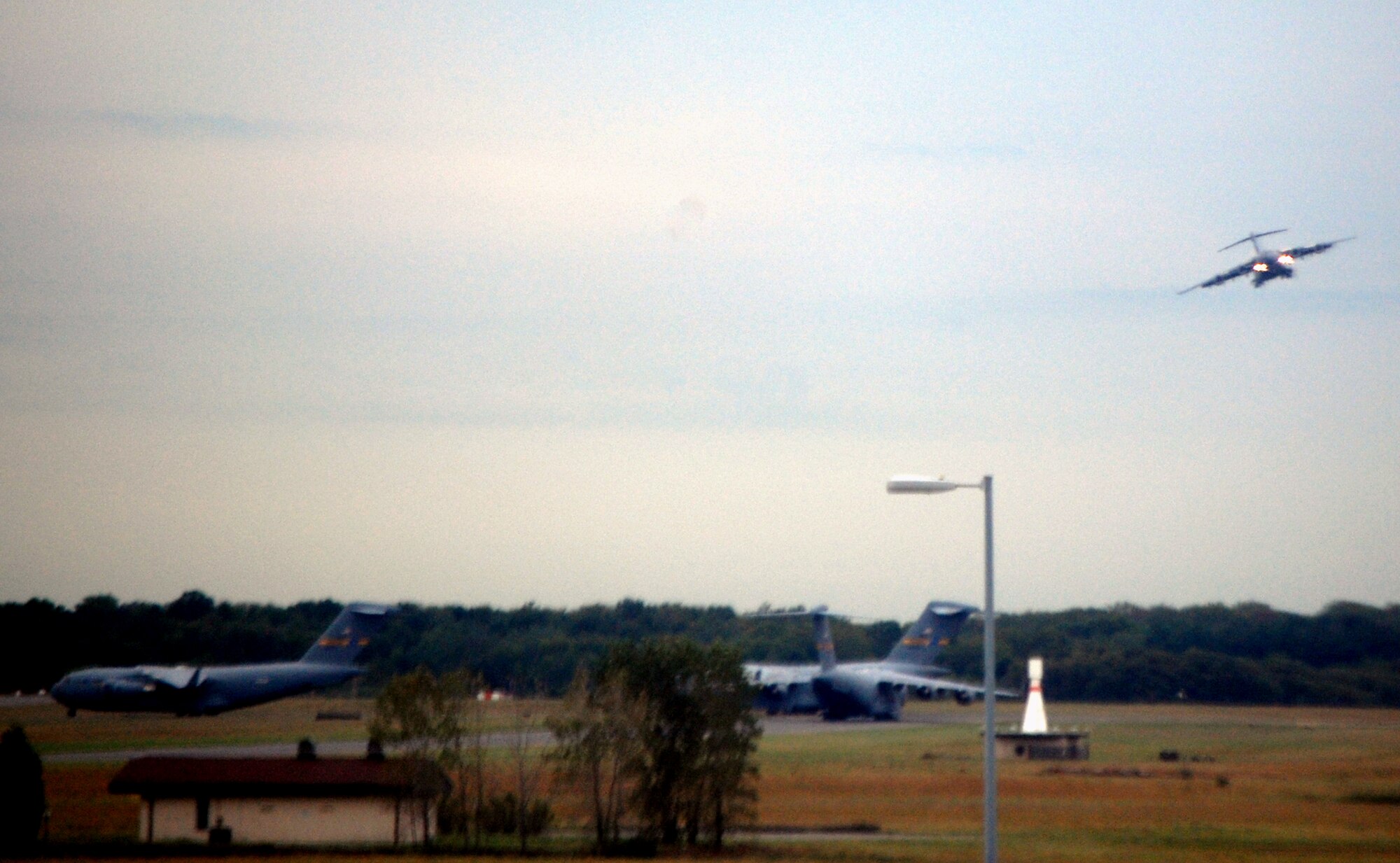 A C-17 Globemaster III comes in for a landing at McGuire Air Force Base, N.J., Sept. 16, 2008, while another three C-17s prepare for take-off.  The C-17 is the main airlift plane at McGuire which helps Air Mobility Command and the Air Force to "fly, fight and win...in air, space and cyberspace." (U.S. Air Force Photo/Tech. Sgt. Scott T. Sturkol)
