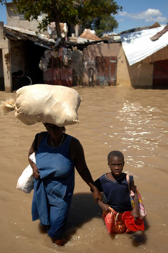 A Haitian woman leads her child through the streets of Gonaives, an area of Haiti devastated by recent hurricanes, Sept. 15, 2008. 