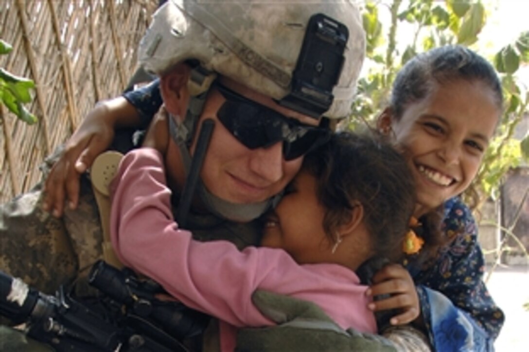 Iraqi children give U.S. Army Sgt. Joshua Kowalik hugs as he pauses to say hello during a sensing patrol of the Iraqi Family Village, a neighborhood of displaced citizens in Baghdad, Iraq, Sept. 11, 2008. Kowalik  is assigned to the 101st Airborne Division's Headquarters Battery, 1st Battalion, 320th Field Artillery Regiment, 2nd Brigade Combat Team.