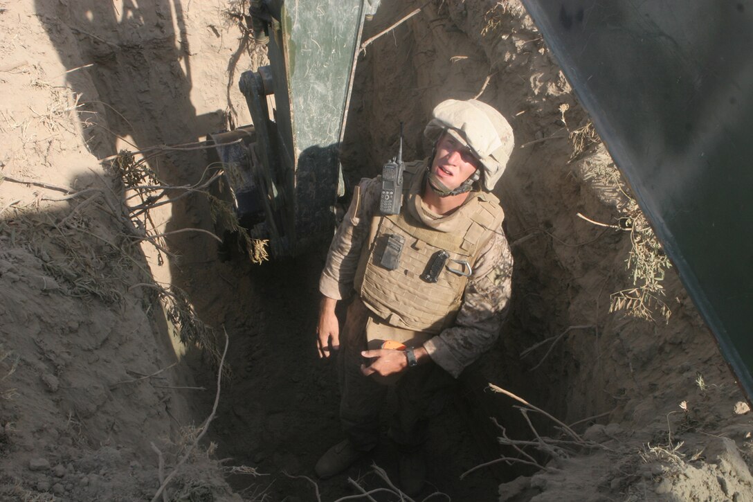 Cpl. Matthew J. Short, a heavy equipment operator with Support Platoon, Company A, 3rd Combat Engineer Battalion, Regimental Combat Team 5, inspects the hole he dug to make sure it is big enough to fit a bridge anchor for the Wahid Bridge in al-Anbar province, Iraq, Sept. 17. The anchors were installed into the banks of the Euphrates River to correct a curve that has developed in the bridge. Marines with Company A and Iraqi Army engineers worked together to put the anchors, which will be tied to the bridge at a later date, in place.::r::::n::
