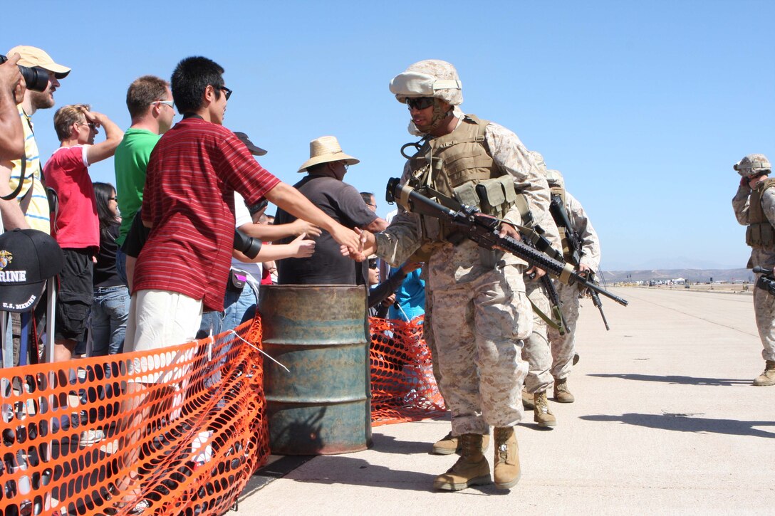 Marines from 1st Battalion, 1st Marine Regiment, 1st Marine Division, shake hand with attendees of the 2009 Marine Corps Air Station Miramar Air Show after performing in the Marine Air-Ground Task Force demonstration. The Marines performed buddy rushes as air craft provided fire support during the demonstration.
