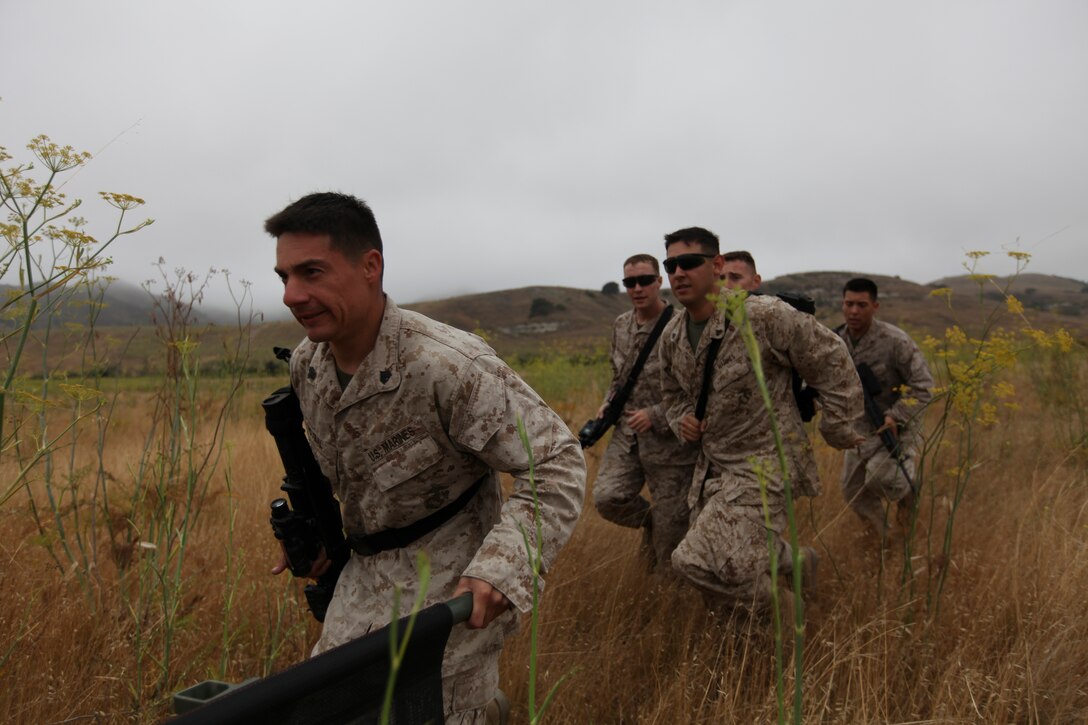 CAMP PENDLETON, Calif. - Marines with the 11th Marine Expeditionary Unit’s command element run to position after evacuating a simulated casualty onto a CH-46 helicopter as part of an aid-and-litter class here July 22. The class was held at the halfway point of an eight-mile hike the 11th MEU was conducting. The conditioning hike was the second the MEU has completed since returning from a deployment in April. (Photo by Cpl. Jeffrey Belovarac)