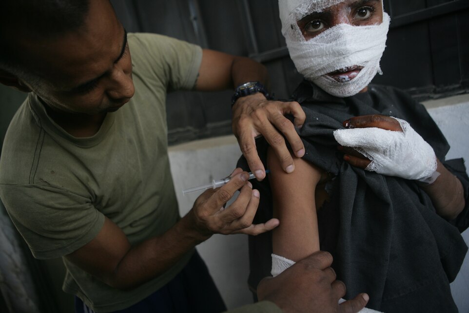 Petty Officer 1st Class Wil Morales, a line corpsman for 2nd Battalion, 7th Marine Regiment, Company F, administers a shot to the Afghanistan boy he helped rehabilitate during 2/7's recent deployment.
