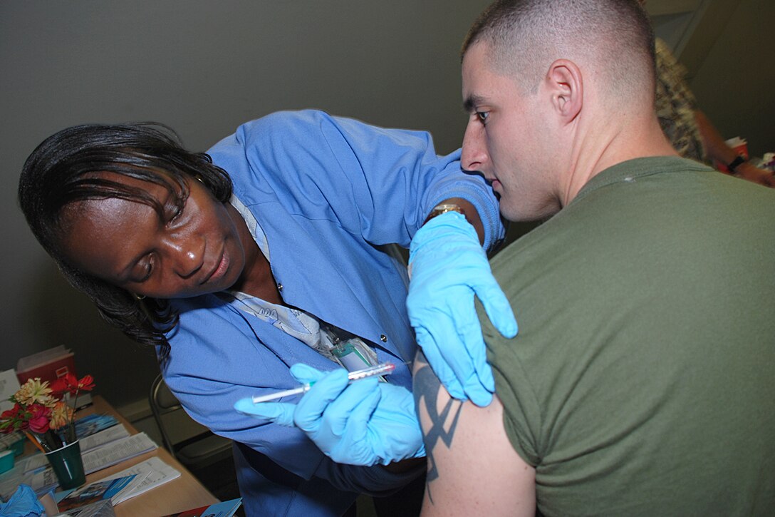 Lydia McVicker, a registered nurse with the Stuttgart Army Health Clinic, gives Sgt. Justin Hensley, a data network specialist with Marine Forces Europe, a vaccine shot during a mental and dental readiness event here, Sept. 18. During the event, the Marines and sailors of Marine Forces Europe were able to review their health records, get up to date on all required immunizations and blood tests, complete a physical health assessment, and receive dental check ups and cleanings.