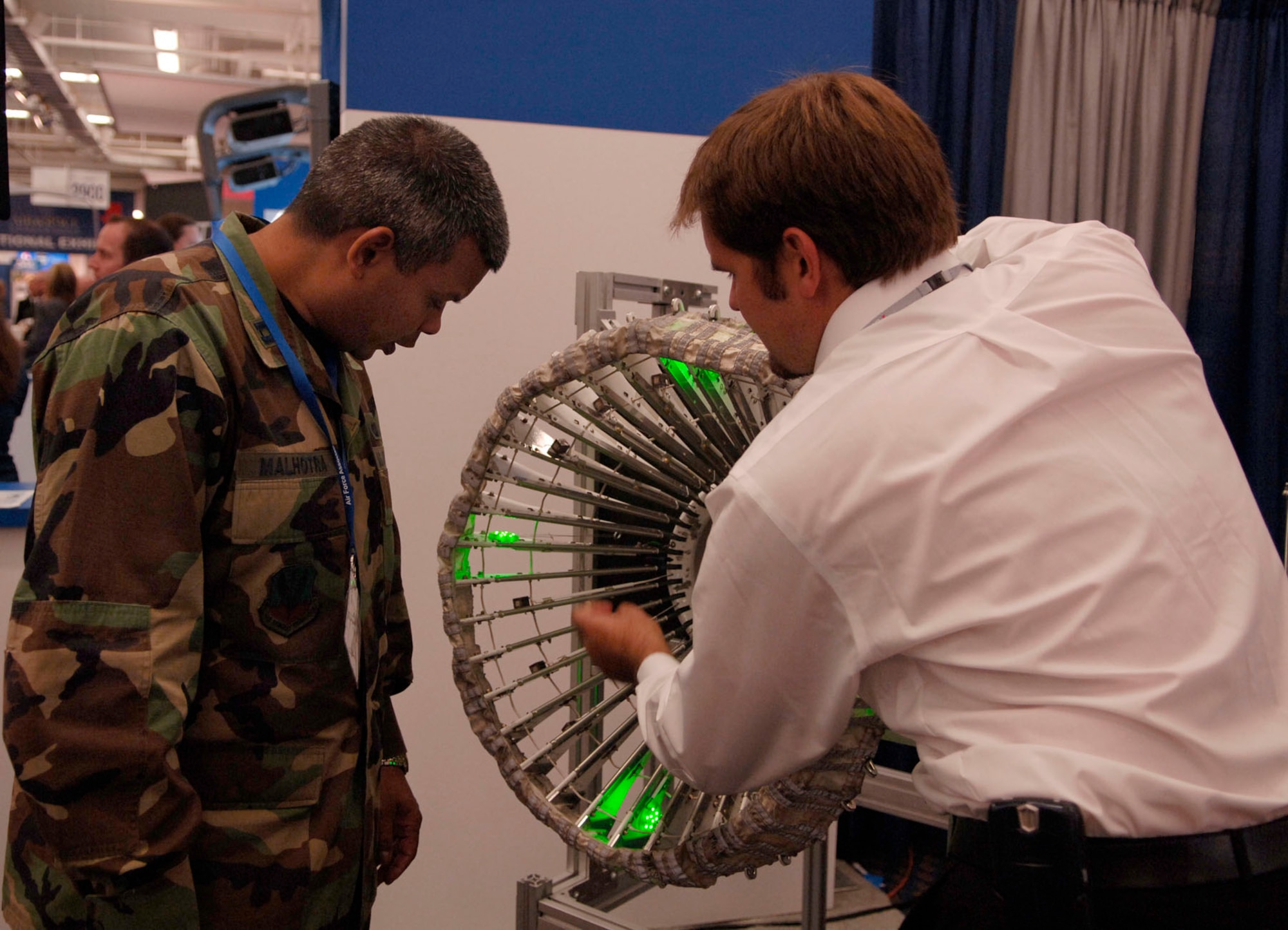 WASHINGTON -- An exhibitor points out parts of a display to Capt. Sanjoy Malhotra during the Air Force Association’s 24th Annual Air and Space Conference and Technology Exposition Sept. 16. A hundred and twenty-five Langley Airmen attended the event. (U.S. Air Force photo/Airman Rebecca Montez)
