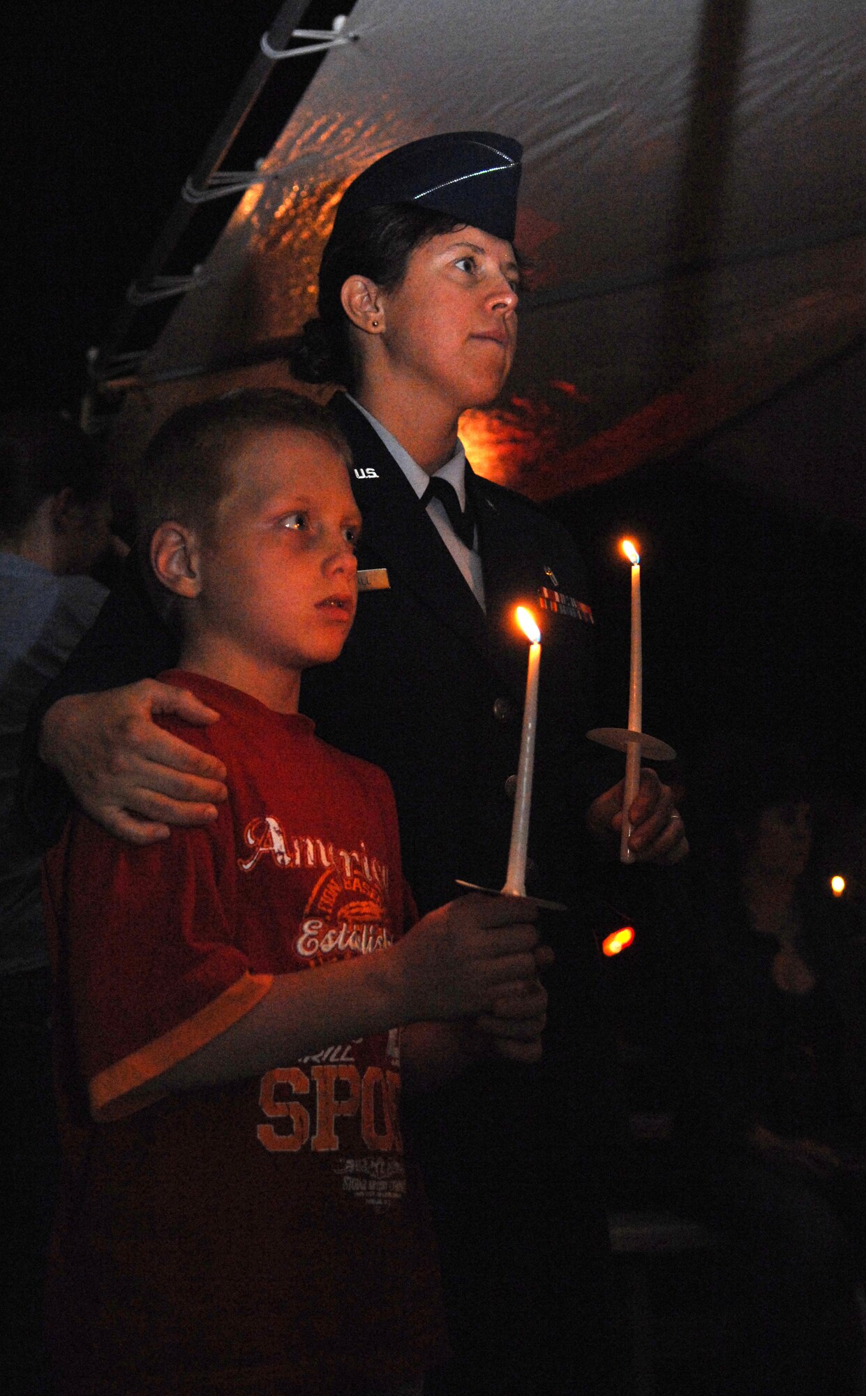 Chaplain (Capt.) Olga Westfall of Holloman Air Force Base, N.M., and her adopted son, Dmitri, pay tribute to the fallen during the candle-lighting at the 9/11 Memorial Ceremony at the New Mexico Museum of Space History, September 11. Dmitri is a new citizen to the U.S., and this was his first time learning about the tragedy on 9/11. According to the chaplain, he was very impressed by the ceremony. (U.S. Air Force photo/Airman Sondra M. Escutia)
