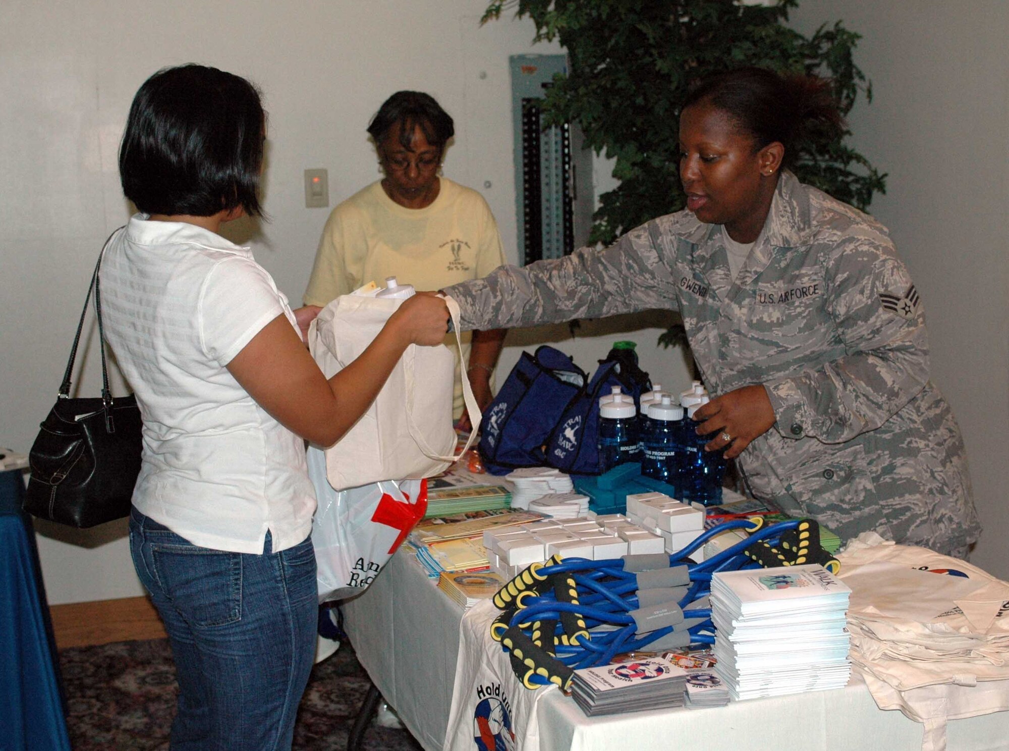 Senior Airman Treshawna Gwendo, 60th Medical Diagnostics and Therapeutic Squadron, hands out free samples from the Health and Wellness Center during the Deployed Spouses Dinner Sept. 16 at the Travis Conference Center. (U.S. Air Force photo/Airman 1st Class Kristen Rohrer)