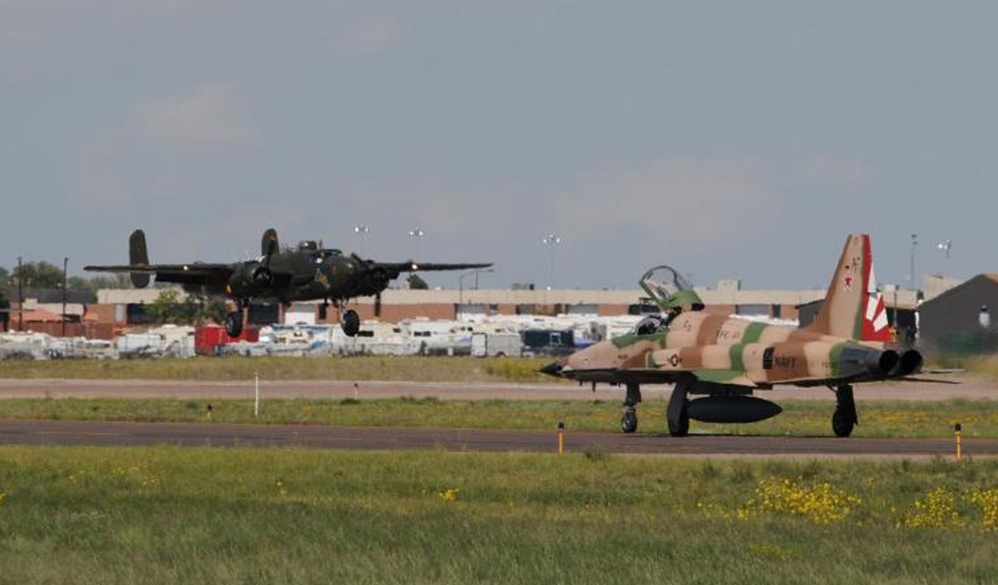 A B-25H Mitchell, known as “Barbie III,” comes in for a landing as a Navy aggressor F-5 taxis nearby. The aircraft was used during a Sept. 6 ceremony of the re-activation of the World War II-era 380th Bombardment Squadron (Medium) as the 380th Space Control Squadron in Colorado Springs, Colo. (Courtesy photo/Rollan Yocum)