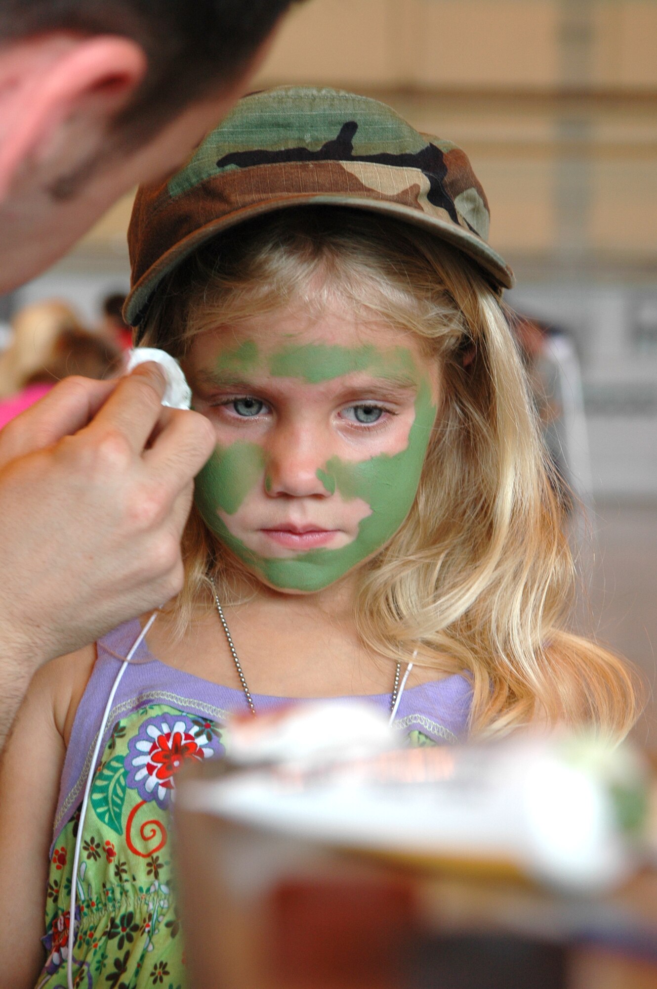 Hannah Breedlove, 5, waits nervously as the first color is applied at the comoflauge station at Camp Courage. Children learned about the deployment process there were two static aircraft-displays, along with vehicles and personnel from Security Forces, the Army and Marine Corps. (Air Force photo/Micah Garbarino)