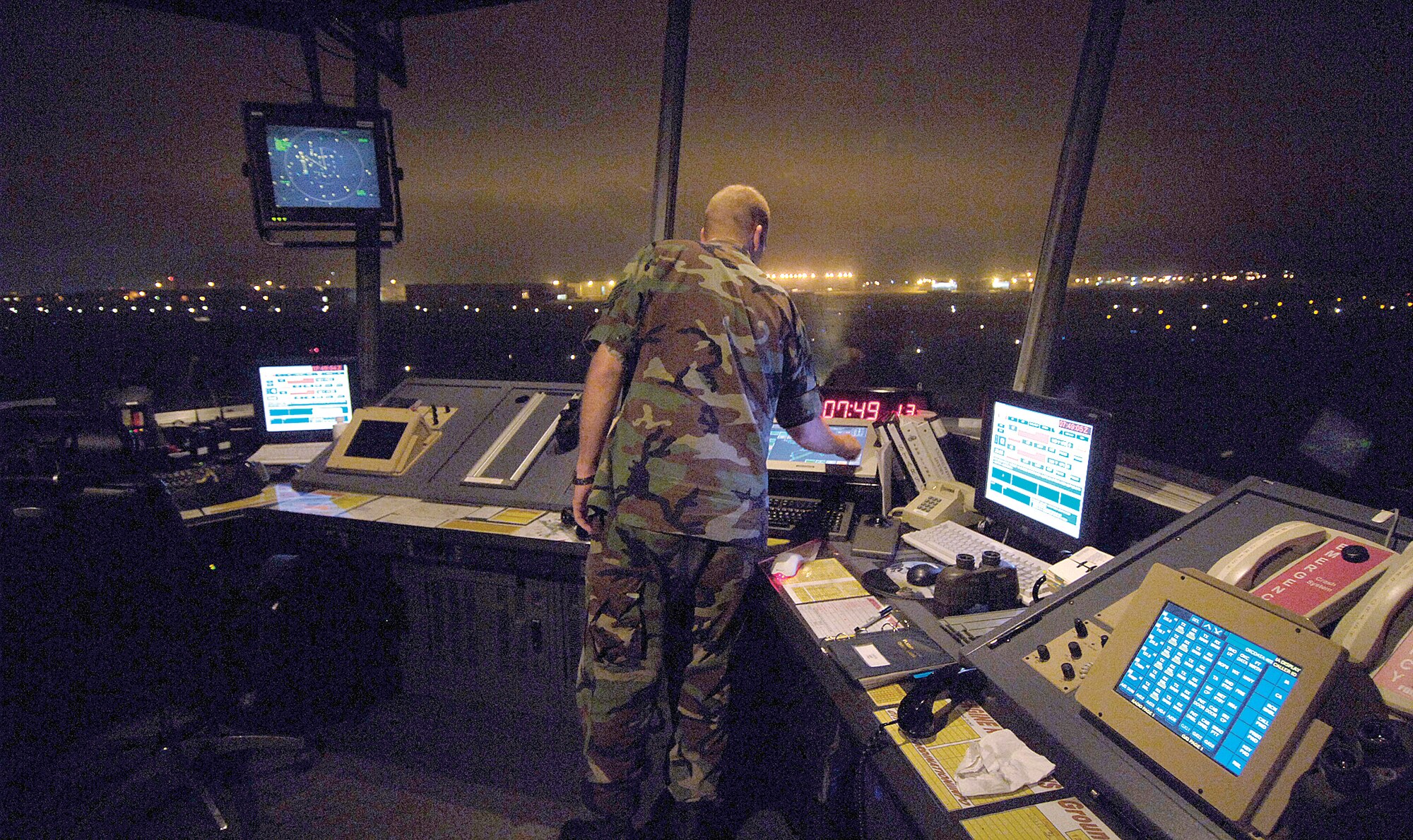 Lights on Tinker buildings dot the horizon seen from  the  Air Traffic Control tower where Staff Sgt. Scott Williams watches the airfield.  Up to five people may work in the tower during days, but Sergeant Williams enjoys the variety and solitude of nights.  Though usually quiet, the watch supervisor knows supporting alert flying squadrons at night is his priority as Tinker’s airfield never closes. (Air Force photo/Margo Wright)