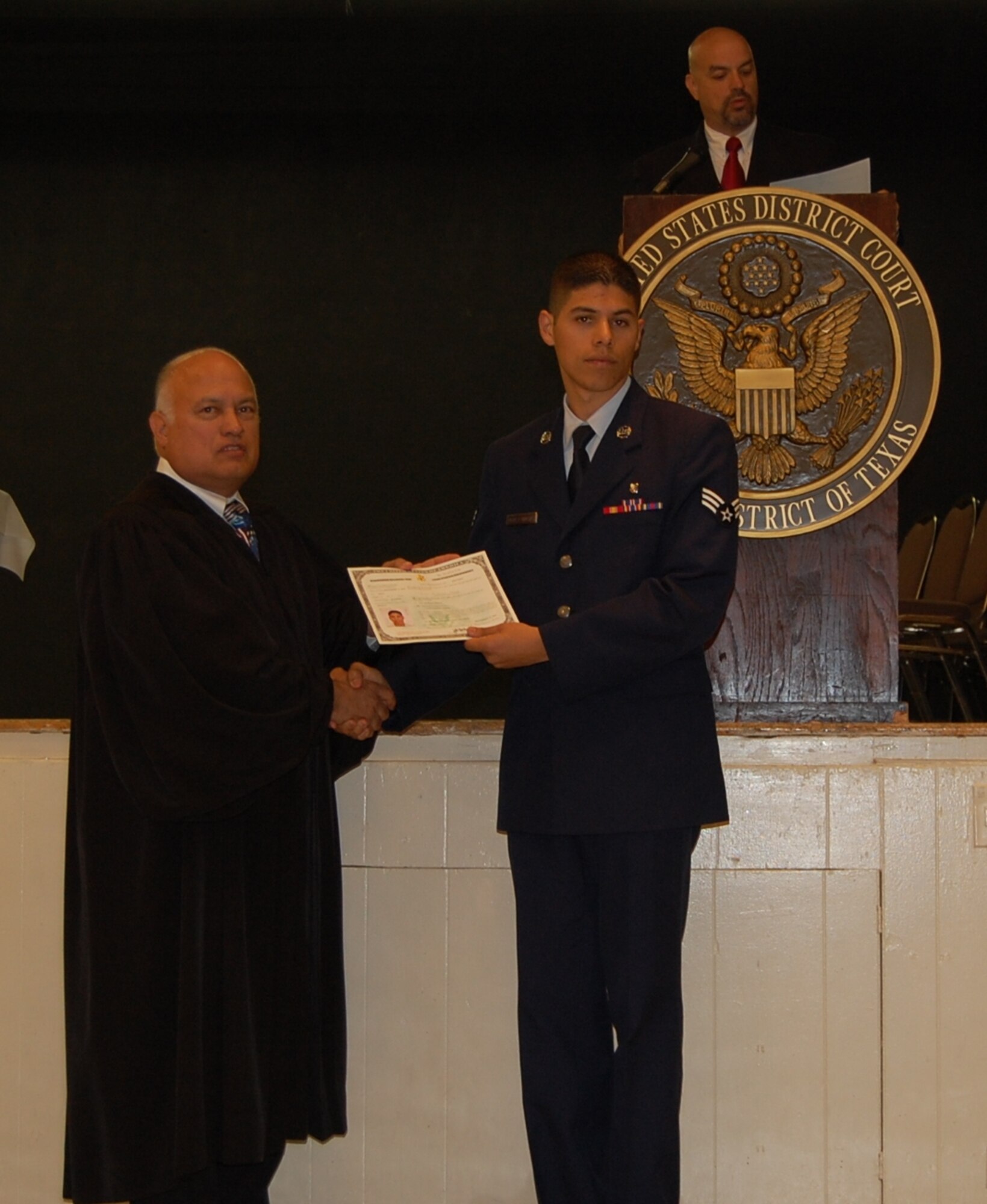 LAUGHLIN AIR FORCE BASE, Texas-- Senior Airman Luis Perez-Macias, 47th Medical Support Squadron medical readiness training manager, receives his naturalization certificate from Victor Roberto García, United States Judge Magistrate in the Del Rio Civic center Sept. 12. (U.S. Air Force photo by 2nd Lt. Cody Chiles)