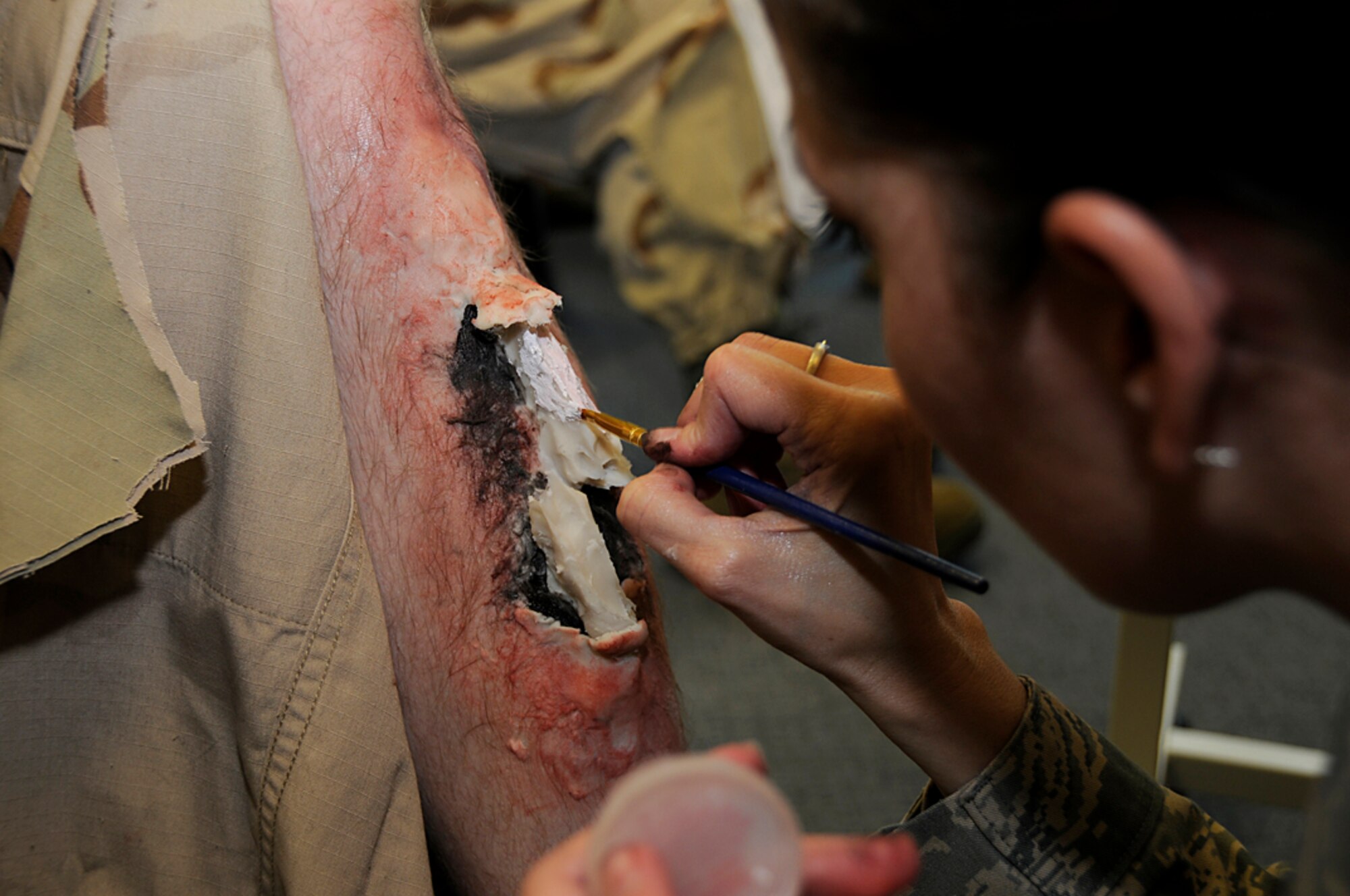 Staff Sgt. Michelle Linn, 48th Medical Support Squadron, creates an open fracture wound on Airman 1st Class Derrick Moreau, 48th Logistics Readiness Squadron, in preperation for a mass casualty exercise at RAF Lakenheath, England, Sept. 11. Sergeant Linn volunteered her time and talent to create realism for the exercise. (U.S. Air Force photo by Senior Airman Brian J. Ellis)