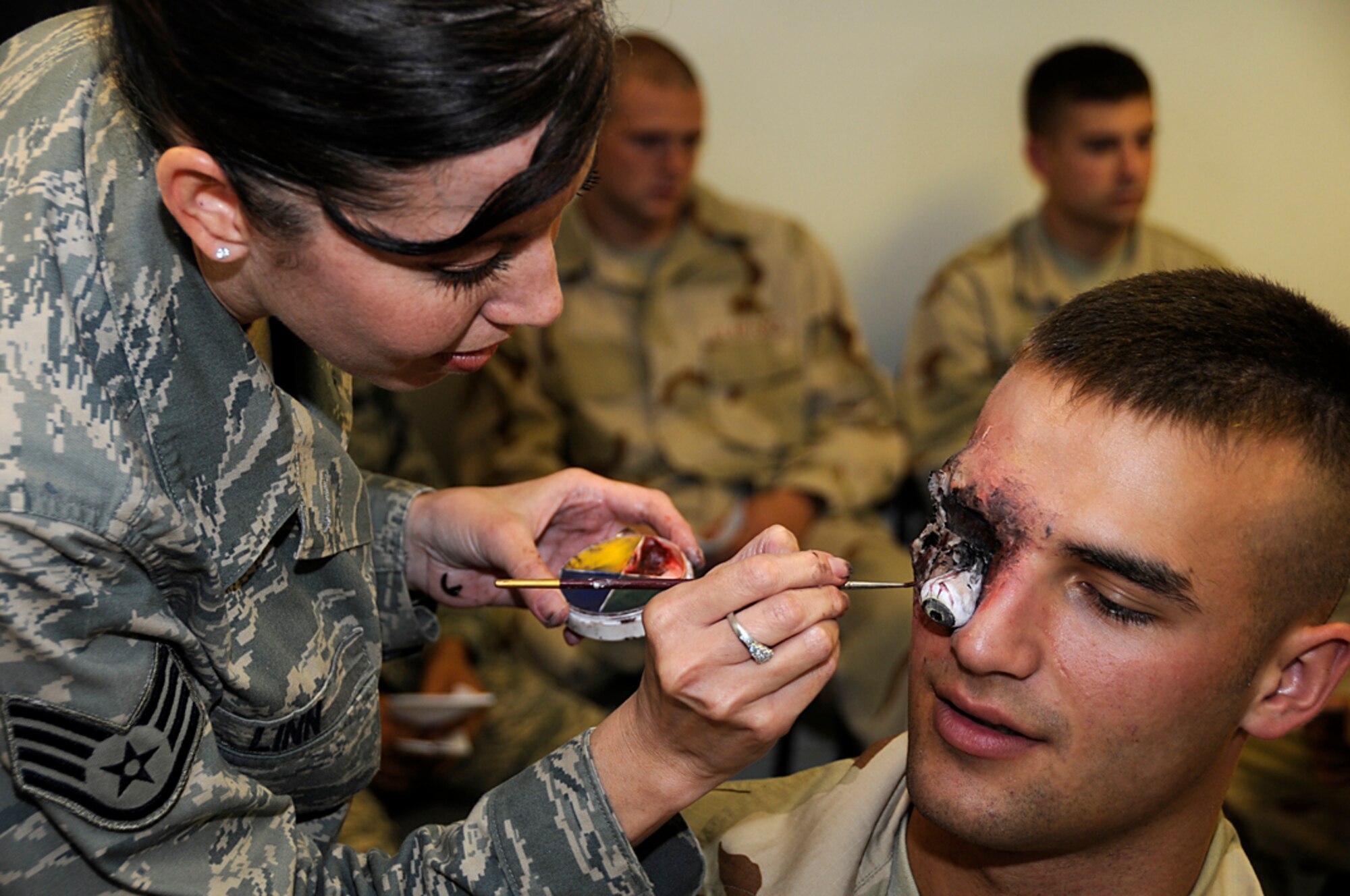 Staff Sgt. Michelle Linn, 48th Medical Support Squadron, puts finishing touches on an eye-ball used to simulate an injury on Airman Scott Menadue, 48th Security Forces Squadron during a mass casualty exercise at RAF Lakenheath, England, Sept. 11. Sergeant Linn volunteered her time and talent to create realism for the exercise. (U.S. Air Force photo by Senior Airman Brian J. Ellis)