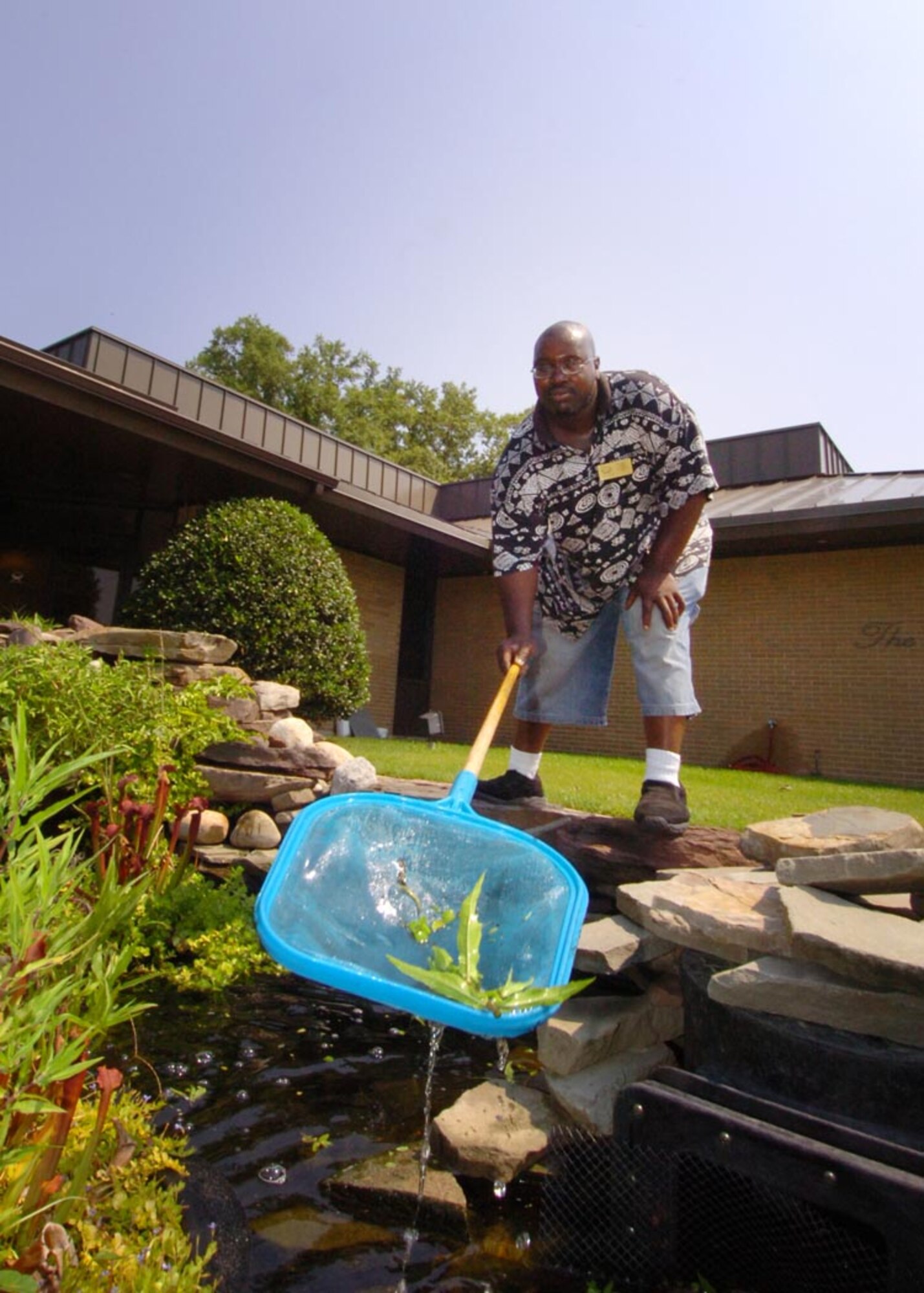 Mr. Tyler uses a net to fish out plant debris after handgrooming the exotic fish exhibit at The Courses at Andrews.