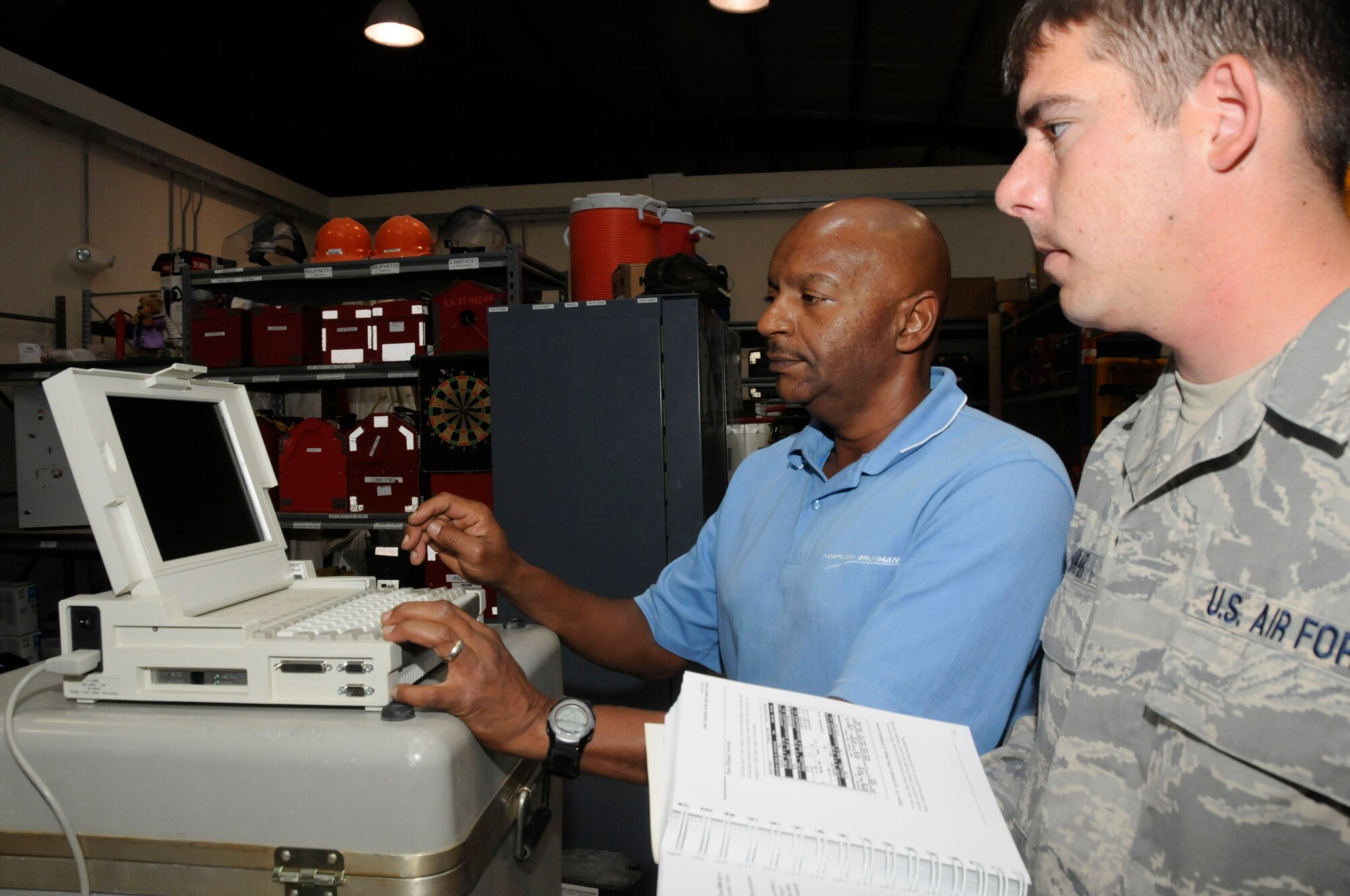 Mr. Greg Snell, field service representative working for Northrop Grumman, inputs data into a Local Area Network analyzer while Staff Sgt. Justin Mauhar, surveillance radar technician assigned to the 379th Expeditionary Aircraft Maintenance Squadron, checks operating instructions Sept. 17, 2008, at an undisclosed air base in Southwest Asia. Mr. Snell is a native of Warner Robins, Ga., and Sergeant Mauhar is a native of Clarkston, Wa.  Both are deployed from Robins Air Force Base, Ga., supporting Operations Iraqi Freedom, Enduring Freedom and Joint Task Force-Horn of Africa. (Photo by Staff Sgt. Darnell T. Cannady/Released)