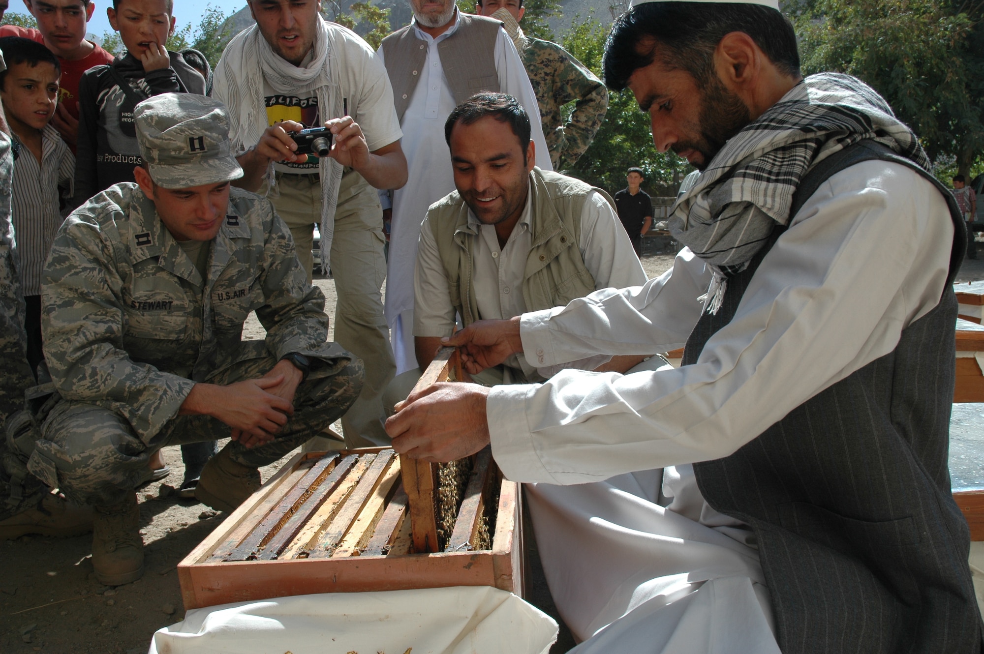 Beekeeper Mir Weiss shows Capt. Jayson Stewart, Panjshir Provincial Reconstruction Team Director of Operations a sleeve of bees from one of the bee boxes during the bee delivery ceremony Sept. 17 at Bazarak High School, Bazarak District.  One hundred and fifty bee boxes were delivered to Bazarak District as part of an overall $180,000 province-wide project to help the local economy and boost agricultural production.(U.S. Air Force photo by Capt. Jillian Torango)