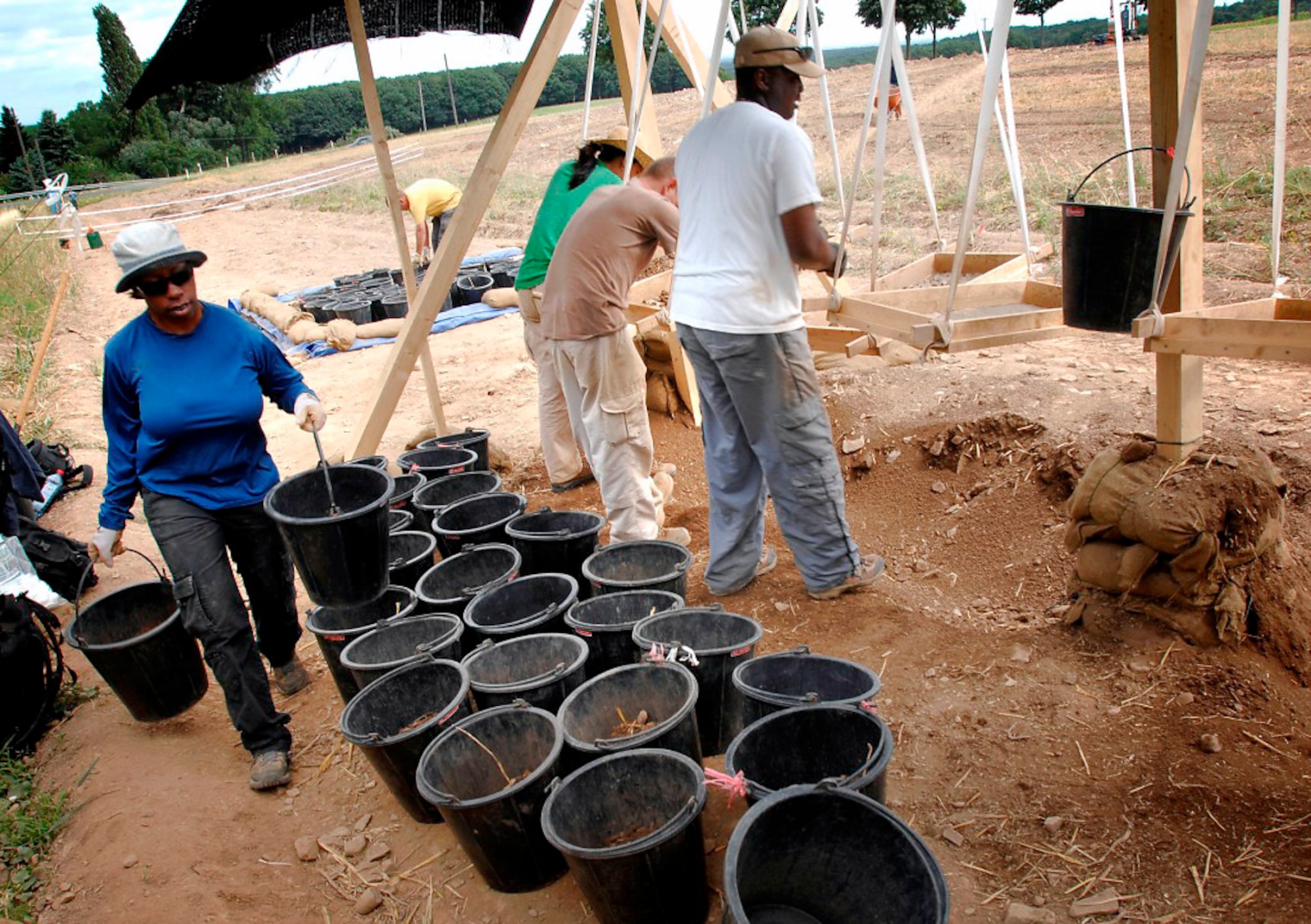Tech. Sgt. Valda Wilson hauls buckets of dirt to the screening station so that it can be filtered for human remains as well as other evidence that would lead to the identification of a missing servicemember. Sergeant Wilson is an Air Force photographer. (Department of Defense photo/Fred W. Baker III) 
