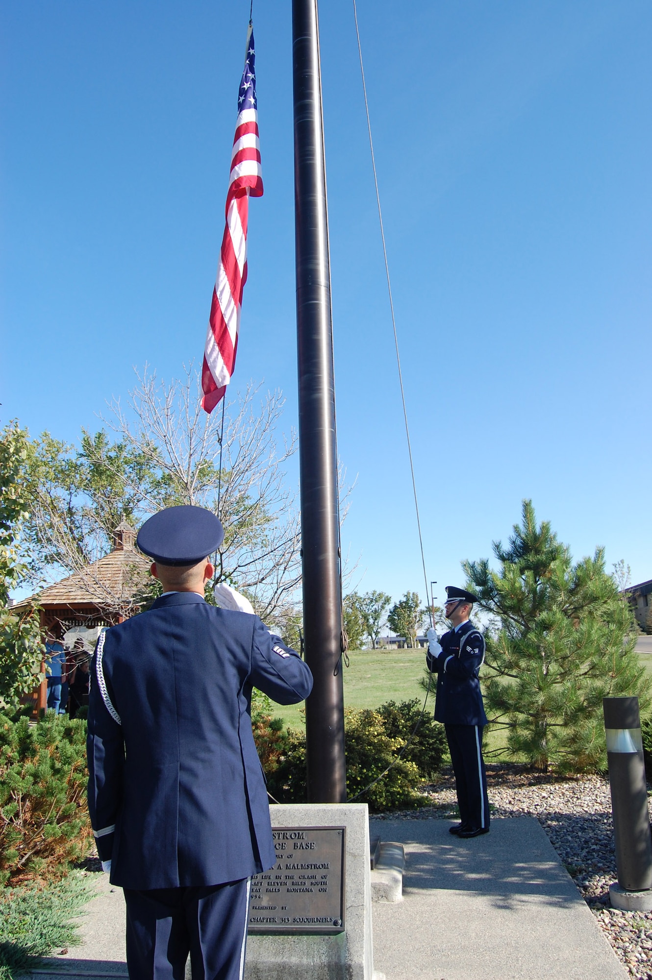 A member of the Honor Guard salutes the flag as two other members lower it during a POW/MIA retreat ceremony at Medal of Honor park Sept. 17 (U.S. Air Force photo/Senior Airman Emerald Ralston)