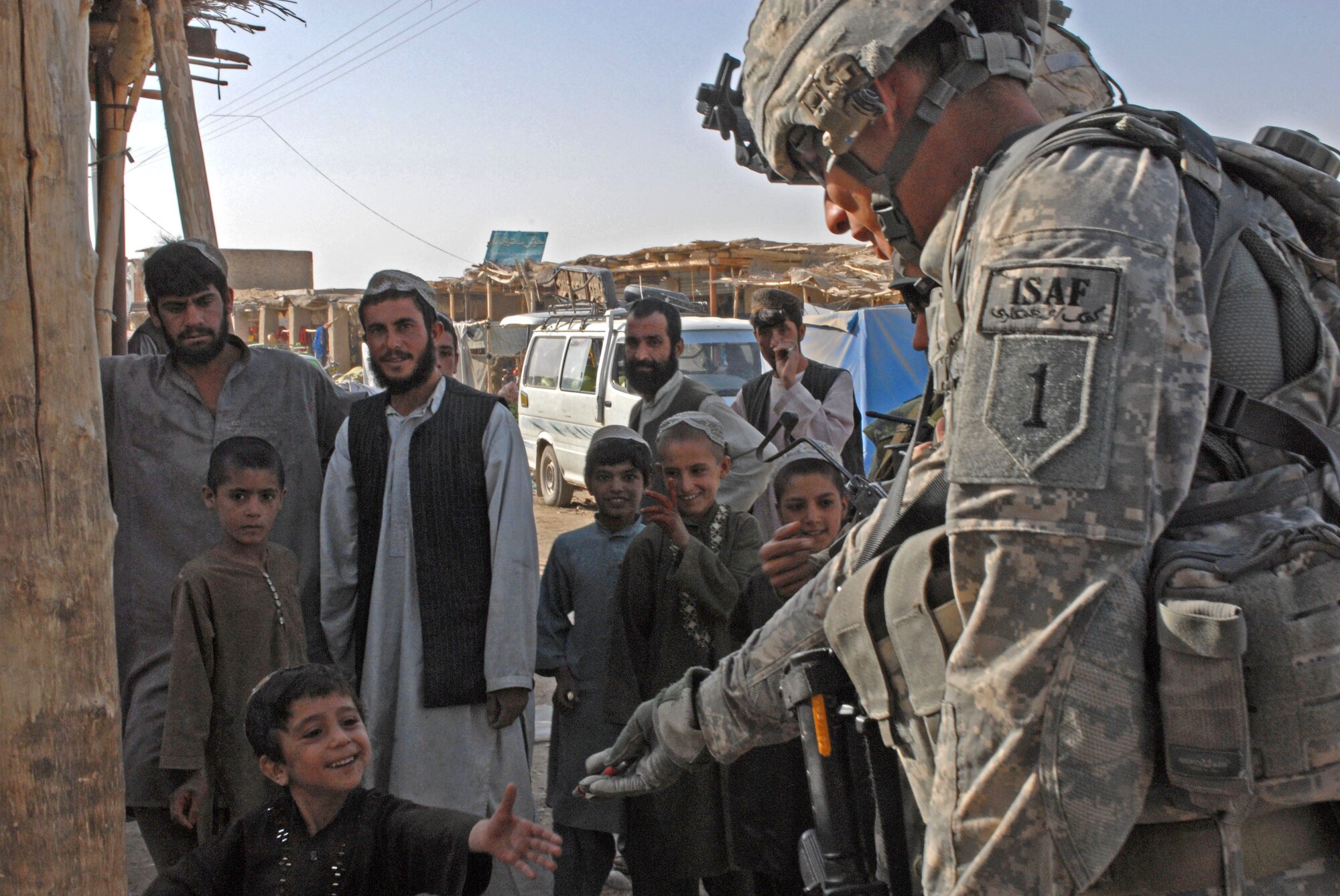 Sgt. Raymond Diaz, a 2-2 Inf. Reg. Soldier gives an Afghan boy a pen, a desired object among the Afghan children, during a visit to a bazaar in the Maywand District of Afghanistan, Aug 29. 2-2 Inf. Reg. Soldiers secured the area, enabling Coalition forces to interact with the local community. 