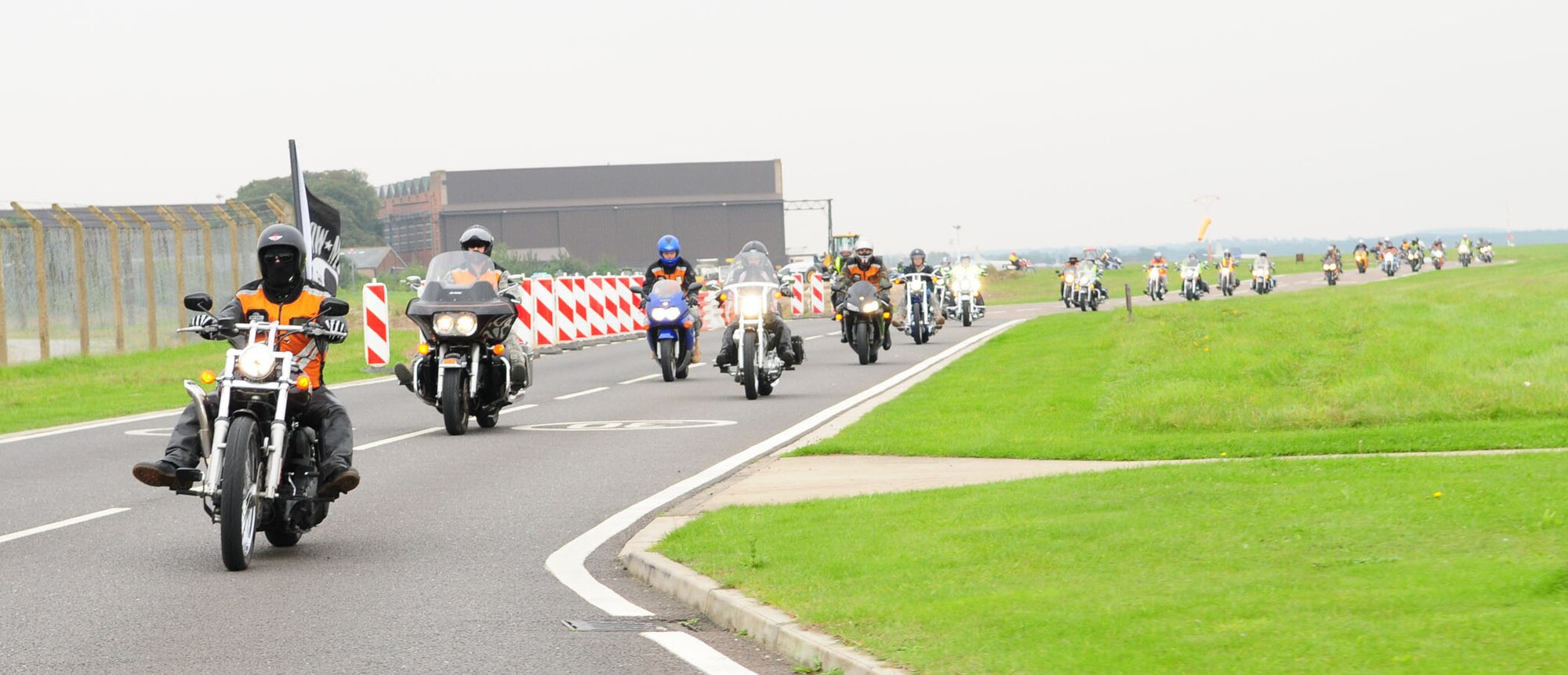 Staff Sgt. Jonathon Richichi, 48th Communications Squadron, is lead motorcyclist Sept. 16 as he carries the Prisoner of War/Missing in Action flag on his bike while leading 51 other motocycles along the perimeter road on RAF Mildenhall as they head off base. After laying a wreath on base, the motorcyclists headed to Mildenhall High Town, where Squadron Leader Rick Fryer, RAF Station Commander, laid a wreath at the British war memorial. The bikers then headed to RAF Lakenheath and laid another wreath at Memorial Park. (U.S. Air Force photo by Karen Abeyasekere)