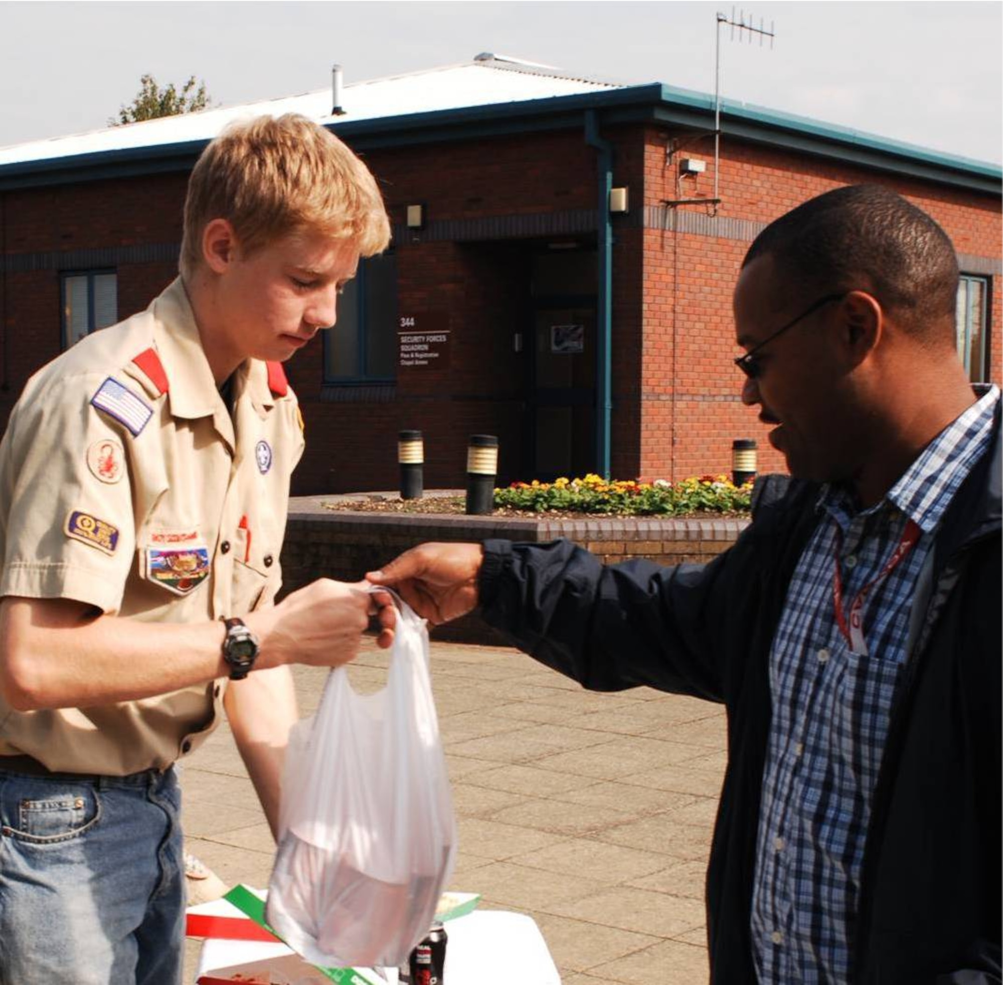 Life Scout Anthony Devlin of Boy Scout Troop 245 accepts a donation of food from a member of the JAC.  Life Scout Devlin collected warm winter clothing, blankets, and food in support of St Theresa's Homeless Day Shelter in Peterborough, England as part of his Eagle Scout project.  (U.S. Air Force photo by Staff Sgt. Chad E. Chisholm)