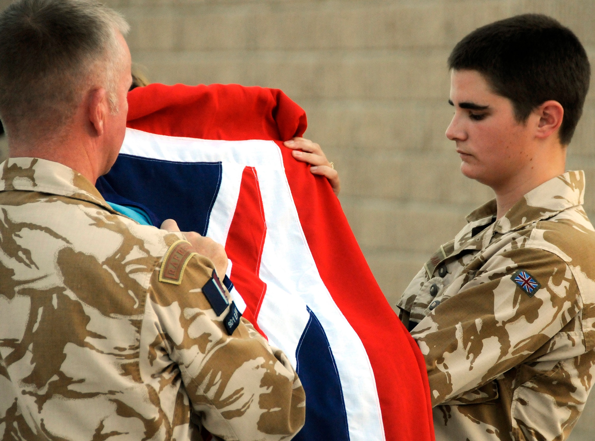 Flight Sgt. Paul Holroyd (left) and Senior Aircraftsman Richie Whelan fold the flag during the Battle of Britain Sunset Ceremony here Sept. 15. The sunset ceremony is a traditional Royal Air Force Ceremony at which the Royal Air Force Ensign is lowered at the end of the day and is used as an act of remembrance for those who fell in the line of duty during the 1940 Battle of Britain. (U.S. Air Force photo By Tech. Sgt. Michael Boquette)