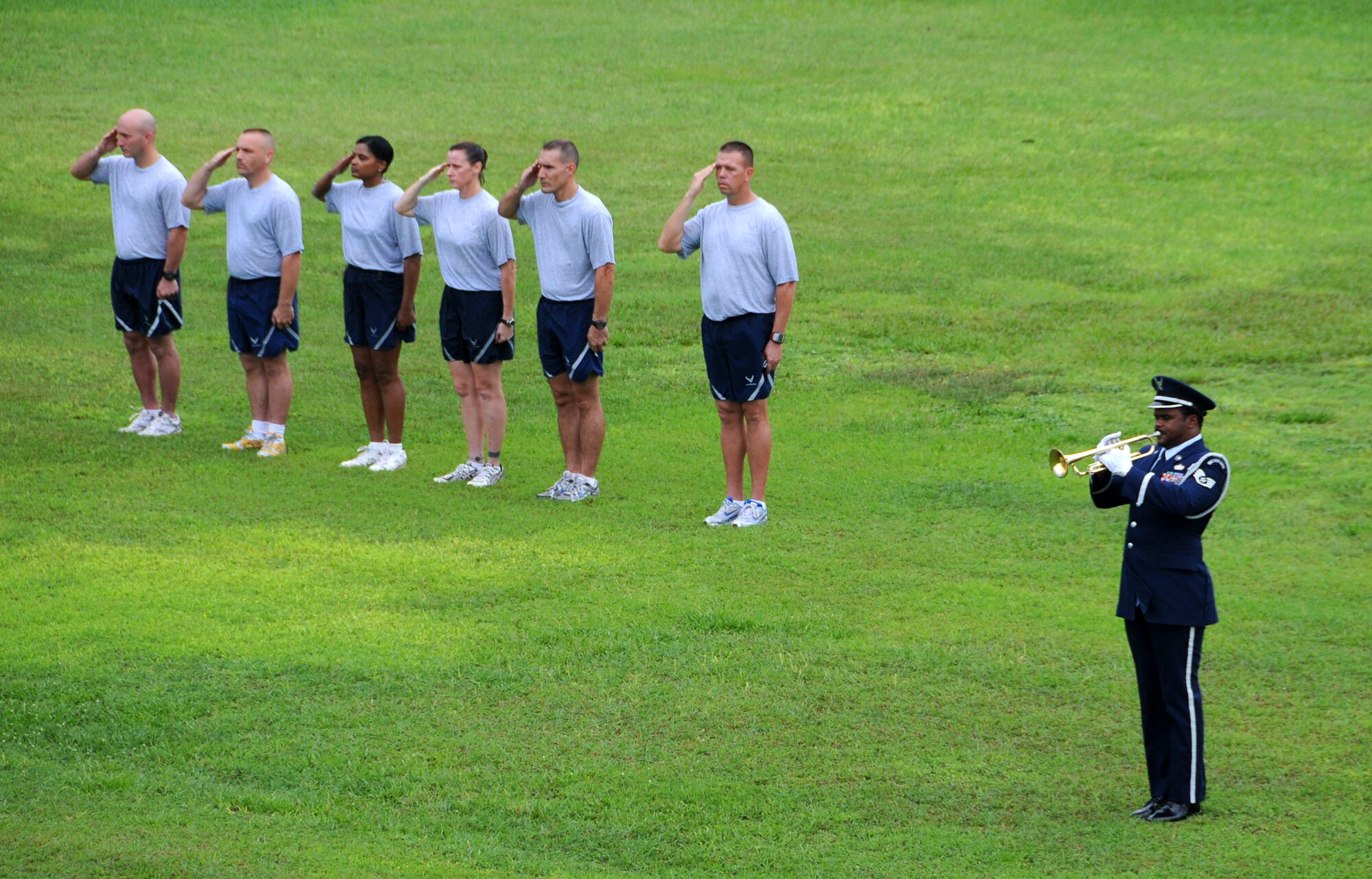 ANDERSEN AIR FORCE BASE, Guam -- Team Andersen's first ergeants salute as an  honor guard member plays "Retreat" during the POW/MIA Retreat Ceremony here Sept. 19. The first sergeants had just finished the last lap of the 24-hour remembrance run at Arc Light Memorial Park. (U.S. Air Force photo by Airman 1st Class Courtney Witt)