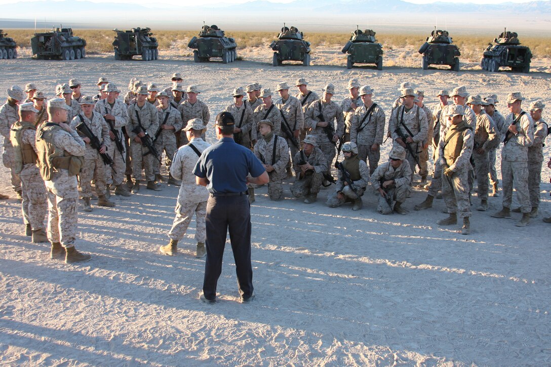 Marines with Company D, 3rd Light Armored Reconnaissance Battalion, stand in a school circle around one of the civilian contractors as he briefs them on their mission for the day’s training.  3rd LAR recently received Improved Thermal Sight Systems and Electric Drive Turrets in their light armored vehicles.