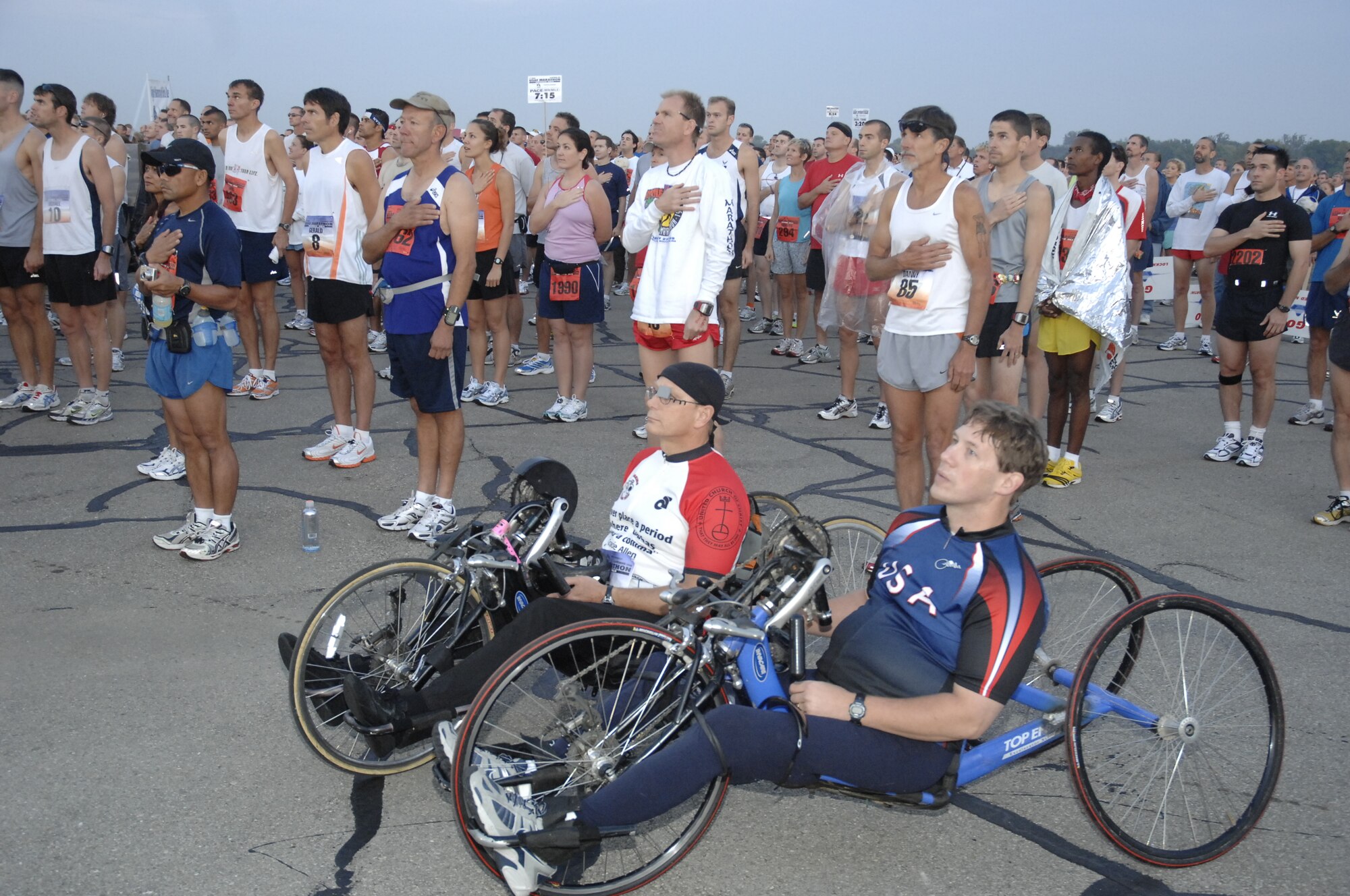 Runners and wheel marathoners honor the playing of the National Anthem and arrival of the American Flag via parachutist, during U.S. Air Force Marathon opening ceremonies at Wright-Patterson Air Force Base Sept. 20. (U.S. Air Force photo/Al Bright)