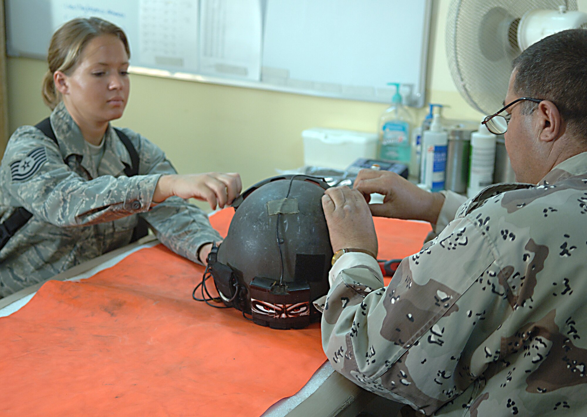 Tech. Sgt. Shaun Cox helps an Iraqi life support technician inspect a helmet at Taji Air Base, Iraq, Sept. 11. Cox, a combat adviser for Iraqi air force flight equipment, is deployed to the 770th Air Expeditionary Advisory Squadron from Luke Air Force Base, Ariz. Her hometown is Lincoln, Neb. (U.S. Air Force photo/Tech. Sgt. Richard Lisum)