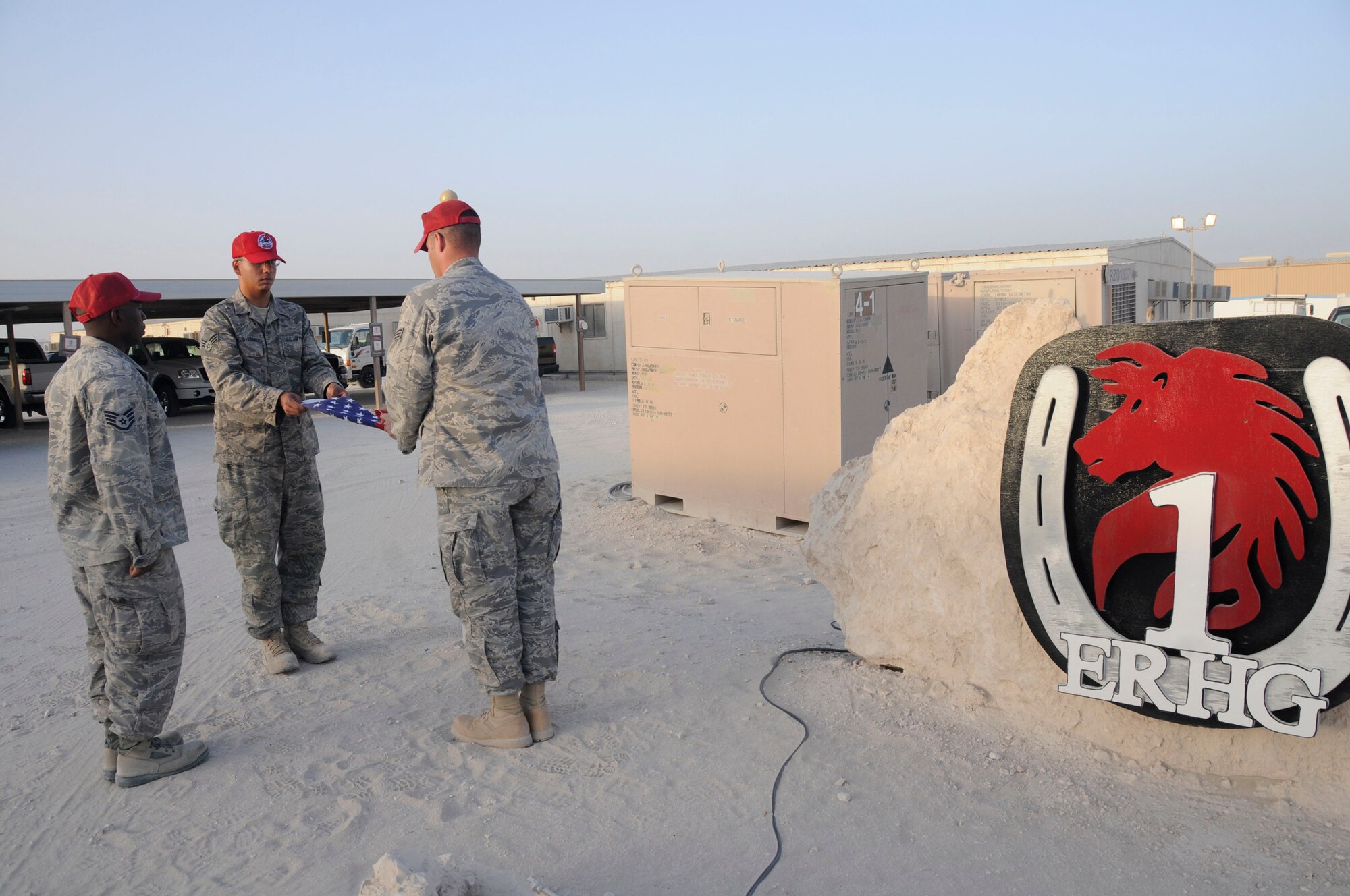 Staff Sgt. LaCourtney Jones waits to call commands while Senior Airman Antonio Santos-Torres and Senior Airman Jason Freytag fold the U.S. flag during retreat Sept. 19, 2008, at an undisclosed air base in Southwest Asia. Airman Santos-Torres is a native of Ponce, Puerto Rico. Airman Freytag is a native of Temple, Texas and Sergeant Jones is a native of Augusta, Ga. All three are supply personnel assigned to the 1st Expeditionary RED HORSE Group deployed in support of Operations Iraqi Freedom, Enduring Freedom and Joint Task Force-Horn of Africa from Hurlburt Field, Fla.  Everyday the RED HORSE Group raises and lowers the flag in front of their compound for reveille and retreat. (U.S. Air Force photo by Staff Sgt. Darnell T. Cannady/Released)