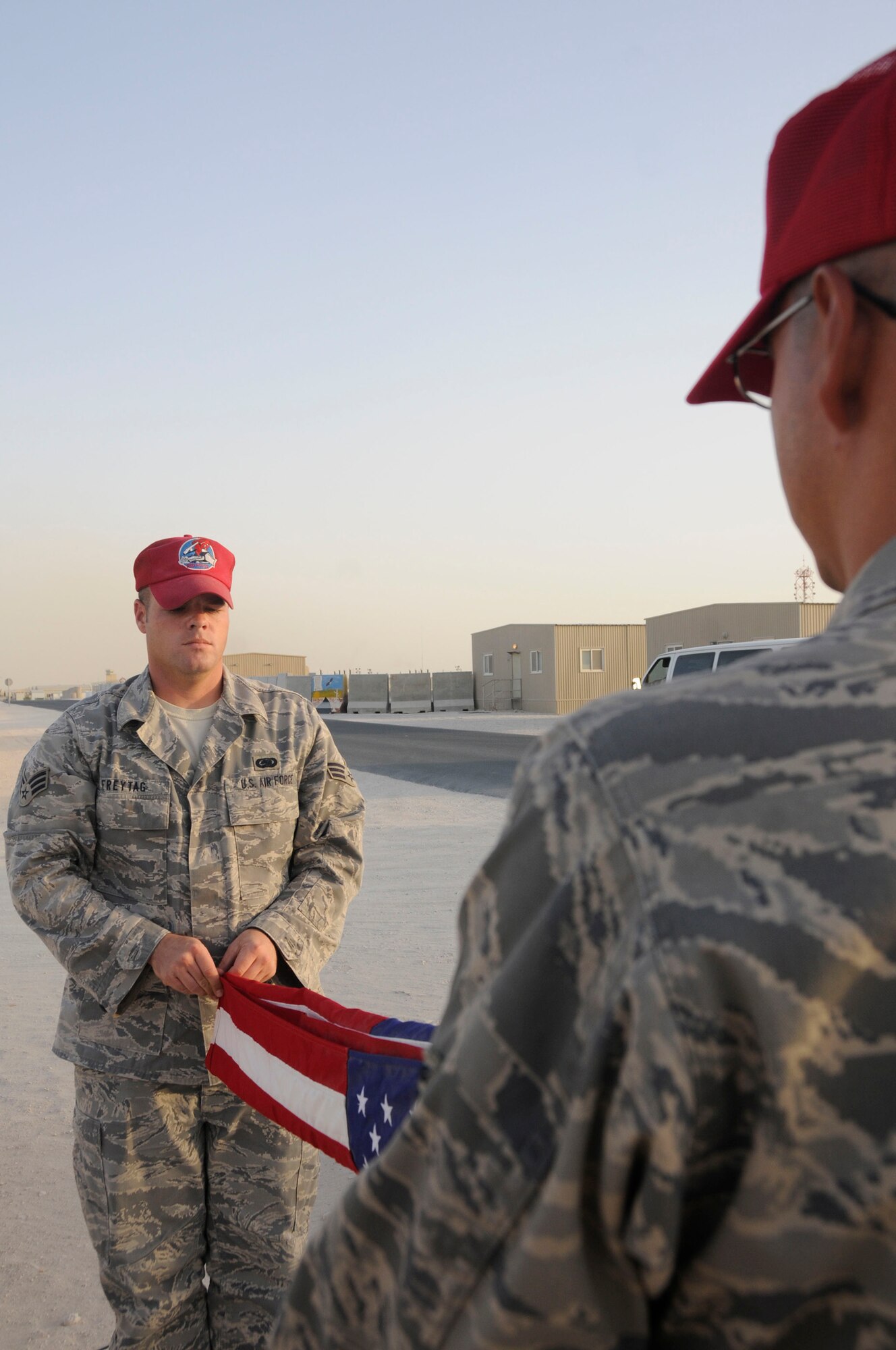 Senior Airman Jason Freytag, and Senior Airman Antonio Santos-Torres, both supply personnel assigned to the 1st Expeditionary RED HORSE Group, fold the U.S. flag during retreat Sept. 19, 2008, at an undisclosed air base in Southwest Asia. Everyday the RED HORSE Group raises and lowers the flag in front of their compound for reveille and retreat. Airman Freytag, a native of Temple, Texas and Airman Santos-Torres, a native of Ponce, Puerto Rico, are both deployed from Hurlburt Field, Fla., supporting Operations Iraqi Freedom, Enduring Freedom and Joint Task Force-Horn of Africa. (U.S. Air Force photo by Staff Sgt. Darnell T. Cannady/Released)