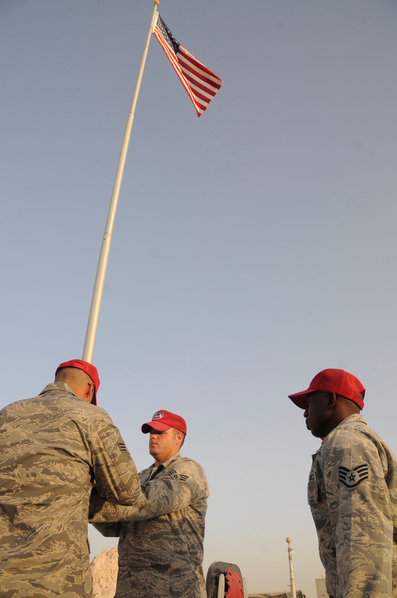 Senior Airman Antonio Santos-Torres and Senior Airman Jason Freytag lower the colors while Staff Sgt. LaCourtney Jones renders a salute during retreat Sept. 19, 2008, at an undisclosed air base in Southwest Asia. Airman Santos-Torres is a native of Ponce, Puerto Rico. Airman Freytag is a native of Temple, Texas and Sergeant Jones is a native of Augusta, Ga. All three are supply personnel assigned to the 1st Expeditionary RED HORSE Group deployed in support of Operations Iraqi Freedom, Enduring Freedom and Joint Task Force-Horn of Africa from Hurlburt Field, Fla.  Everyday the RED HORSE Group raises and lowers the flag in front of their compound for reveille and retreat. (U.S. Air Force photo by Staff Sgt. Darnell T. Cannady/Released)