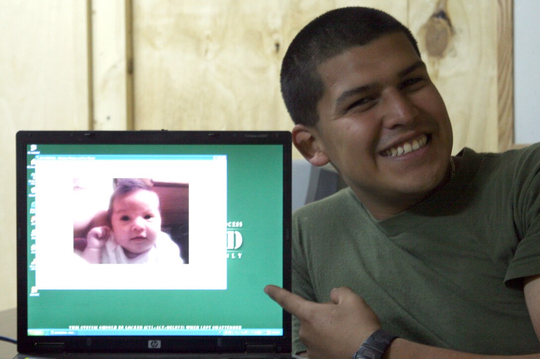 Lance Cpl. Jovan Rodriguez, a warehouse clerk with Task Force 2nd Battalion, 2nd Marines, Regimental Combat Team 5, points to a picture of his daughter Liliana Rodriguez at Camp Al Qa'im, Iraq Sept. 10. Rodriguez got to join his wife through video teleconferencing at Al Asad Air Base for the birth of their first child.  He and his wife were able to see and speak with each other during the entire delivery.