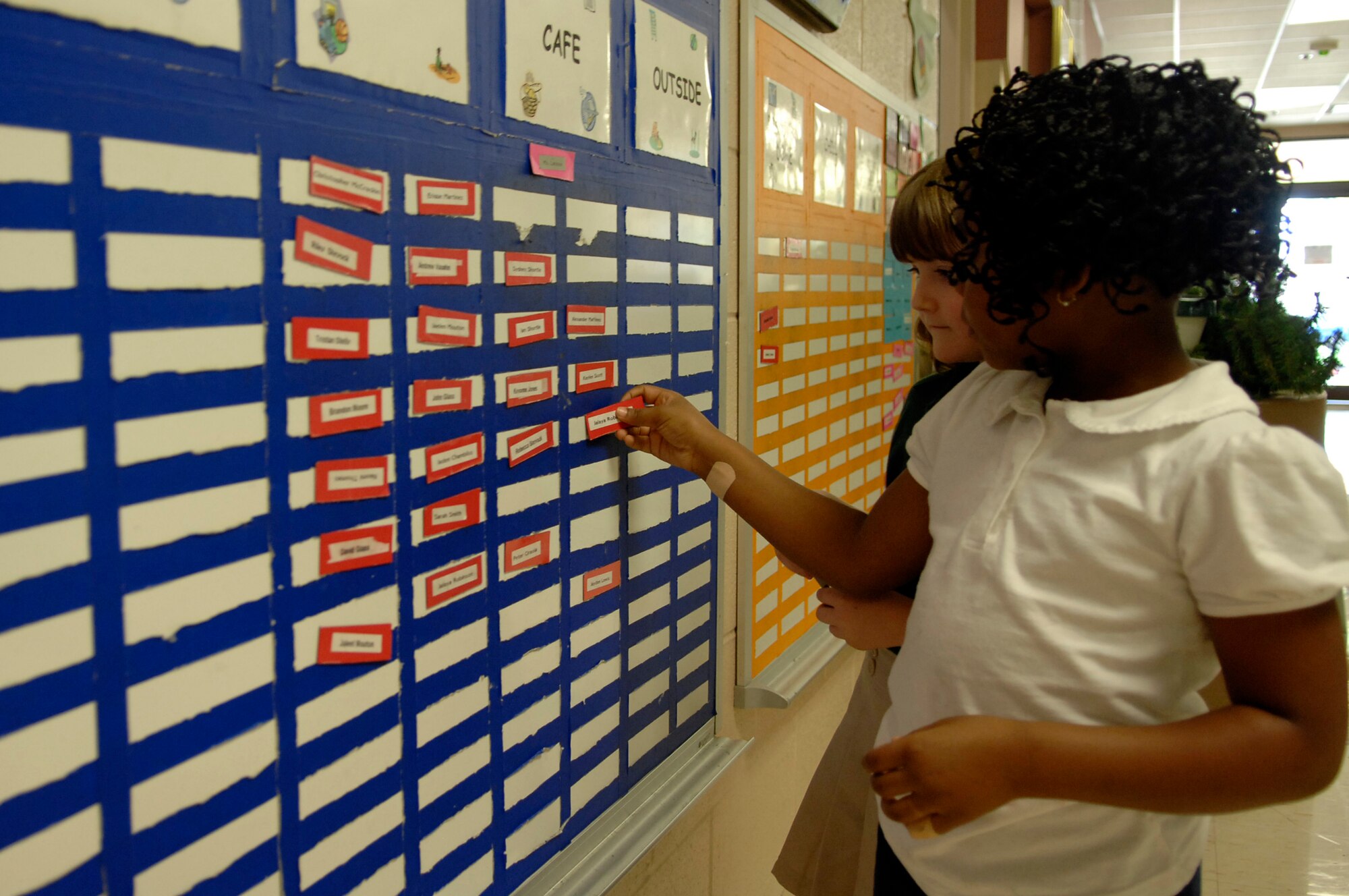 BARKSDALE AIR FORCE BASE, La. - Jayla Robinson, and Kaylee Scott, 1st-graders at Waller Elementary School, place their name tags on a board in the youth center hallway.  The Barksdale Youth Center is now on the Combined Federal Campaign recipient list.  (U.S. Air Force photo by Staff Sgt. Sarah E. Kusek)