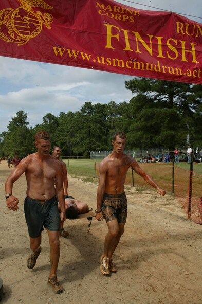 Eastover, S.C.-- Senior Master Sgt. Jason Hines (left), Senior Airman Trevor Brown (right) and Tech. Sgt. Scott Ackeret (back), members of the Shaw Air Force Base Explosive Ordnance Disposal flight, carry teammate, Senior Airman Michael Pasley, in a litter across the finish line of the 15th Annual U.S. Marine Corps Ultimate Challenge Mud Run at the USMC Reserve Center Sept. 20. The team ran the 4.2 mile challenge in 50 minutes and 12 seconds, placing 101st out of approximately 1,200 teams and 9th out of the 53 military teams. (U.S. Air Force photo/Staff Sgt. Holly Brown)
