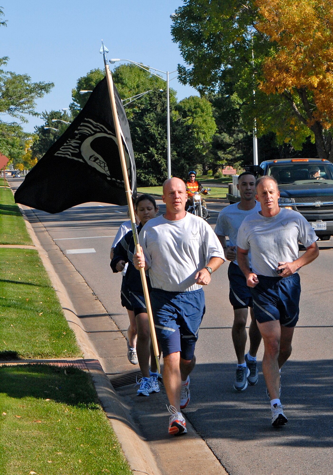 Col. Jay Raymond, 21st Space Wing commander, carries the POW/MIA Flag at the start of the 24-Hour memorial run Sept. 18 following the retreat ceremony at the Peterson Air Force Base Museum in Colorado. The event was used as a forum to inform personnel about POW/MIA Remembrance Week on the base, which ran Sept. 15-19. POW/MIA week allowed members of the installation to remember those held prisoner of war and those missing in action during times of conflict. (U.S. Air Force photo/Craig Denton)