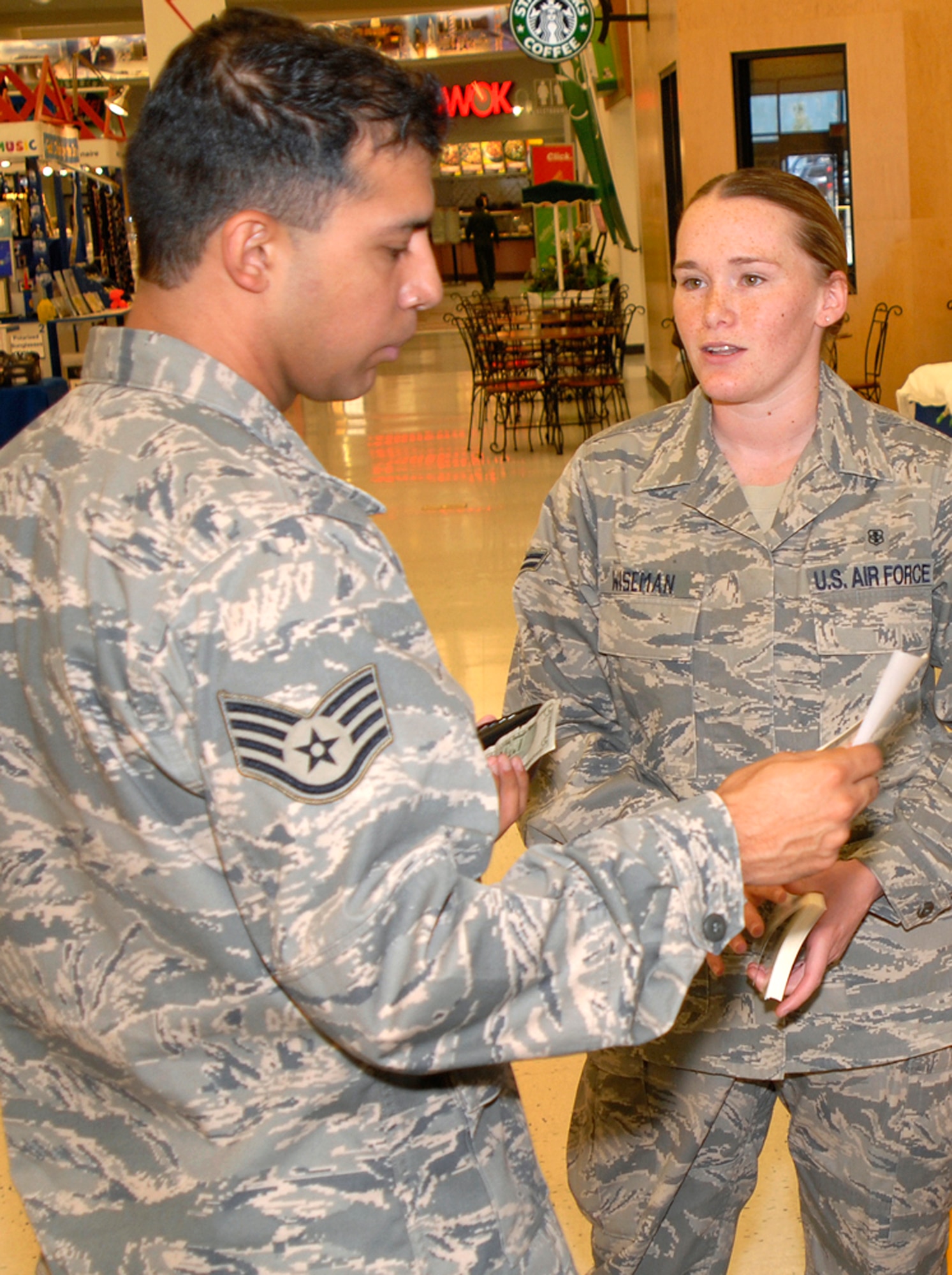 Staff Sgt. Enrique Trevino, 21st Logistics Readiness Squadron, listens on as Airman 1st Class Ladonna Wiseman provides him literature from the POW/MIA information table Sept. 17 at the Peterson Air Force Base exchange. The event was used as a forum to inform personnel about POW/MIA Remembrance Week on the base, which ran Sept. 15-19. POW/MIA week allowed members of the installation to remember those held prisoner of war and those missing in action during times of conflict. Airman Wiseman is assigned to the 21st Dental Squadron. (U.S. Air Force photo/Craig Denton)