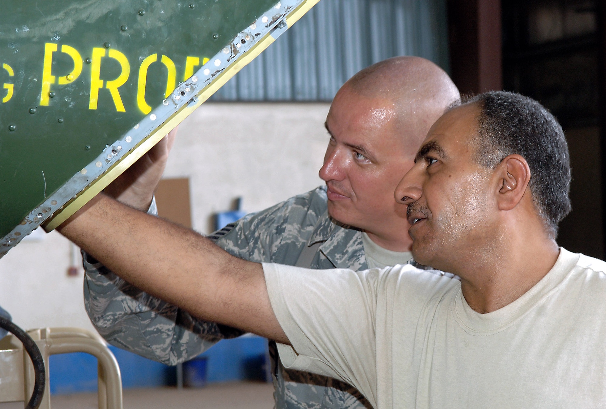 Tech. Sgt. Lee Everhart and Iraqi air force Lt. Col. Auday Yassen Yousif perform maintenance on an Mi-17 Hip helicopter in a hangar Sept. 11 at Taji Air Base, Iraq. The helicopter made a hard landing and struck its tail skid against the ground during a recent training mission, requiring a close inspection of its tail section. Colonel Youssif is chief engineer of second-line maintenance for the Iraqi air force technical wing. Sergeant Everhart, an Mi-17 air adviser with the 770th Air Expeditionary Advisory Squadron, is deployed from Robins Air Force Base, Ga. (U.S. Air Force photo/Tech. Sgt. Richard Lisum) 

