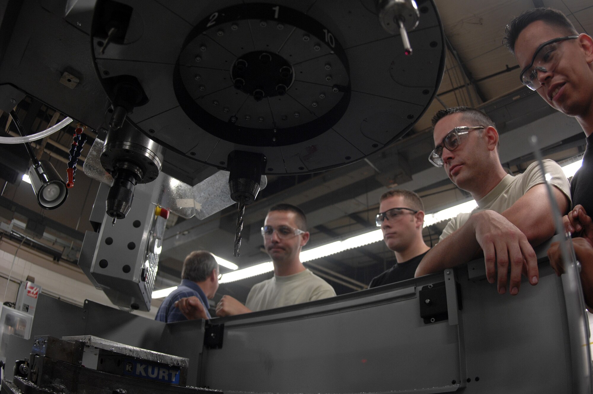 MOODY AIR FORCE BASE, Ga. -- Senior Airman Juan Ruiz, (far right) Airman Michael McClellan, (right) Airman Eric Dininger, (middle) and Staff Sgt. James Gilliland, 23rd Equipment Maintenance Squadron aircraft metals technology, observe how pre-loading tools in a new mill machine assembly saves time during fabrication here August 27.  The group of airmen present during the two day training class will pass on operation knowledge to other airmen throughout the metal workshop to minimize impact on current projects. (U.S. Air Force photo by Senior Airman Javier Cruz)