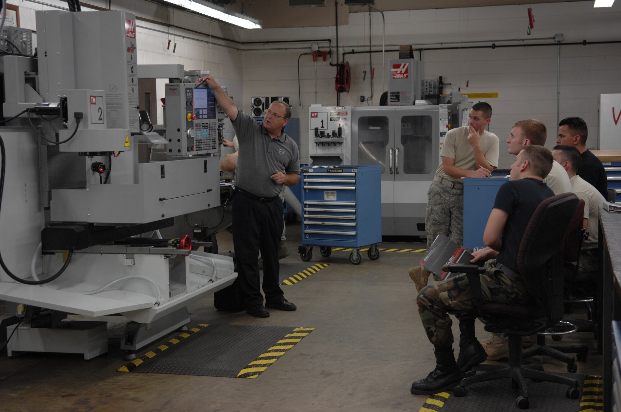 MOODY AIR FORCE BASE, Ga. -- Jeff Foster (left), Philips Corporation computer numerical control applications and education division, instructs five 23rd Equipment Maintenance Squadron aircraft metals technology airmen on how to use and write programs for a new mill machine here August 26. The Airmen are going through two days of functional training with the new machine before training other Airmen. (U.S. Air Force photo by Senior Airman Javier Cruz)