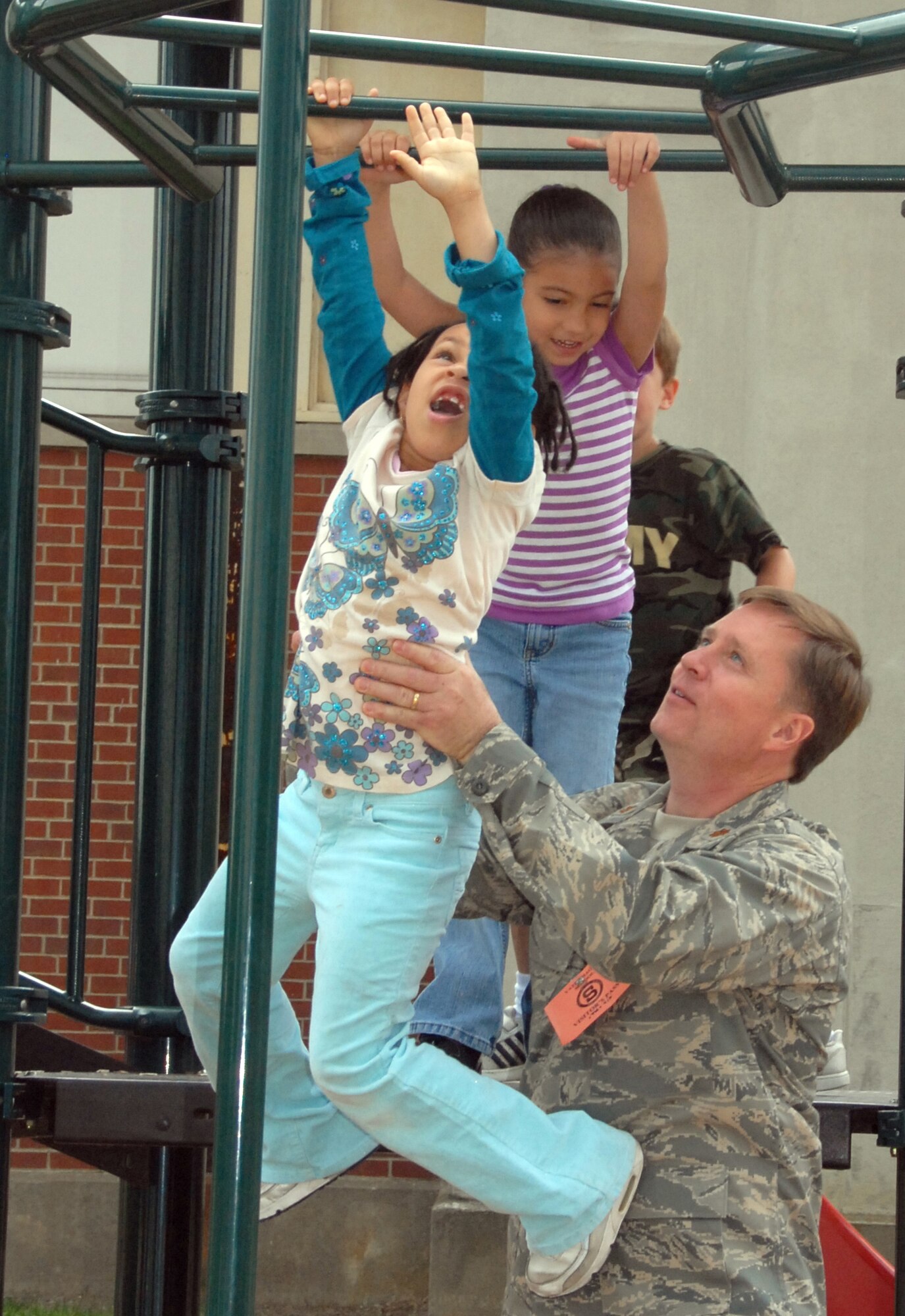 Maj. Mark Armstrong helps a student across the m onkey bars as another girl waits her turn. Guardsmen volunteer to spend lunch with students at Yates Elementary School. (U.S. Air Foce photo by Master Sgt. Christine Wood)