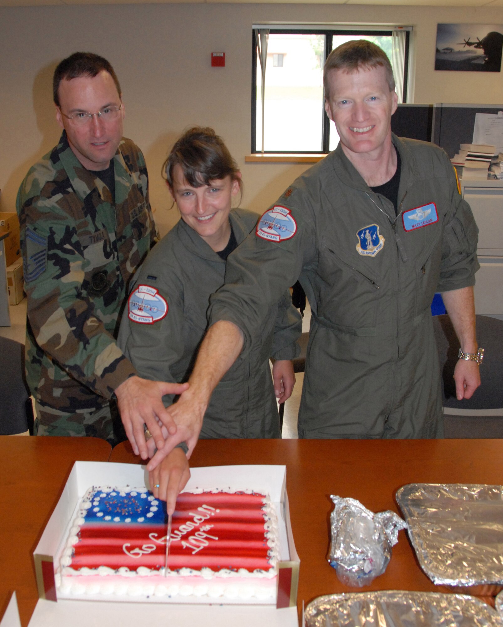 From left, Senior Master Sgt. Christopher Tymula, 1st Lt. Kelly Williams and Maj. Matt LeClair cut into the cake given to them by the staff and students at Yates Elementary School. Dawn Cagnina, who is in charge of the lunch program and has seen the effect the mentors have had on the kids, made the guardsmen a lasagna lunch to thank them for their time with the kids. (U.S. Air Foce photo by Master Sgt. Christine Wood)