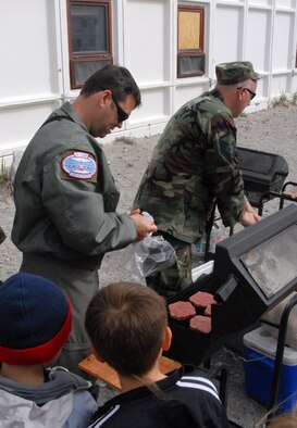 Kids wait patiently as Tech. Sgt. Michael Spiak (left) and Master Sgt. Pete Latniak grill some hamburgers during a community day 109th Airlift Wing members organized for the Greenland school. (U.S. Air Force photo by Master Sgt. Christine Wood)