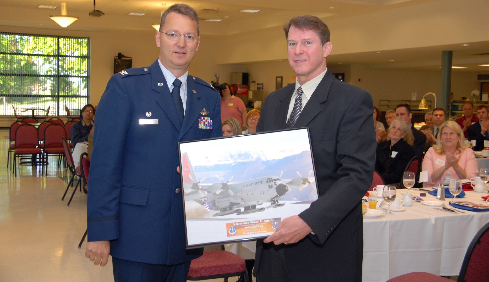 Col. Anthony German presents Rep. Michael McNulty with a photo of the base's LC-130 aircraft during a breakfast ceremony here. McNulty represents the 21st Congressional District. (U.S. Air Force photo by Master Sgt. Willie Gizara)