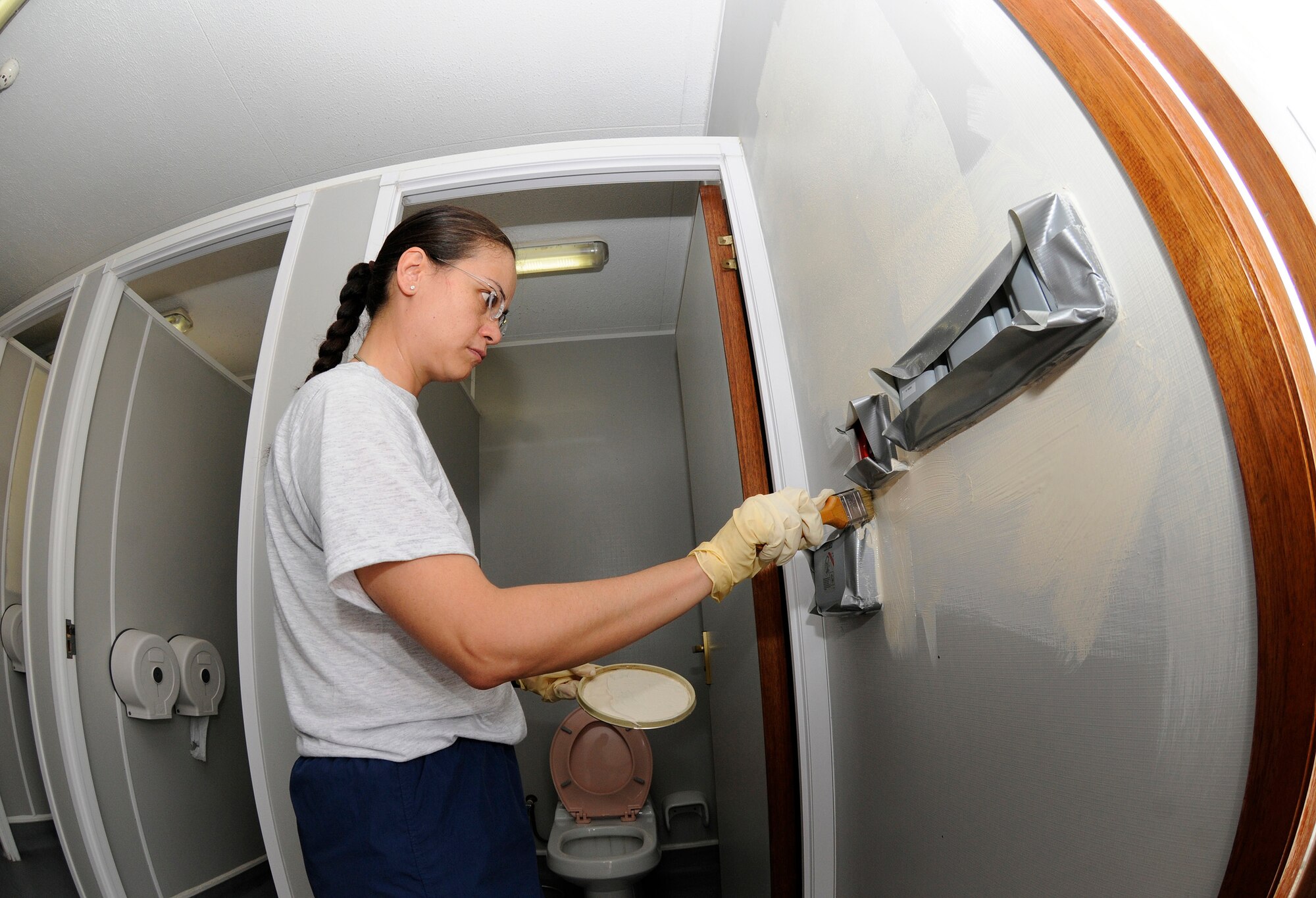 Maj. Louise Shumate, commander of the 379th Expeditionary Comptroller Squadron, paints around fixtures during an effort to take ownership and bring up to Air Force standards the outdoor latrine facility located nearest her office Sept. 21, 2008.  Maj. Shumate volunteered her day off to help thoroughly clean, scrape, sand and paint the restroom facility as part of a clean up operation at an undisclosed air base in Southwest Asia.  Maj. Shumate hails from Crestview, Fla., and is permanently assigned here in support of Operations Iraqi and Enduring Freedom and Joint Task Force-Horn of Africa.  (U.S. Air Force photo by Tech. Sgt. Michael Boquette/Released)