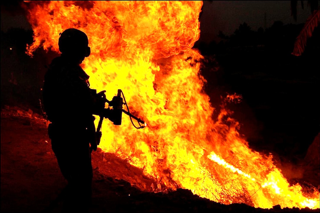 A U.S. Army soldier uses a flamethrower to ignite a controlled fire to eliminate brush from roadsides so bombs cannot be concealed, near Al Anaflsah, Iraq, Sept. 11, 2008. 